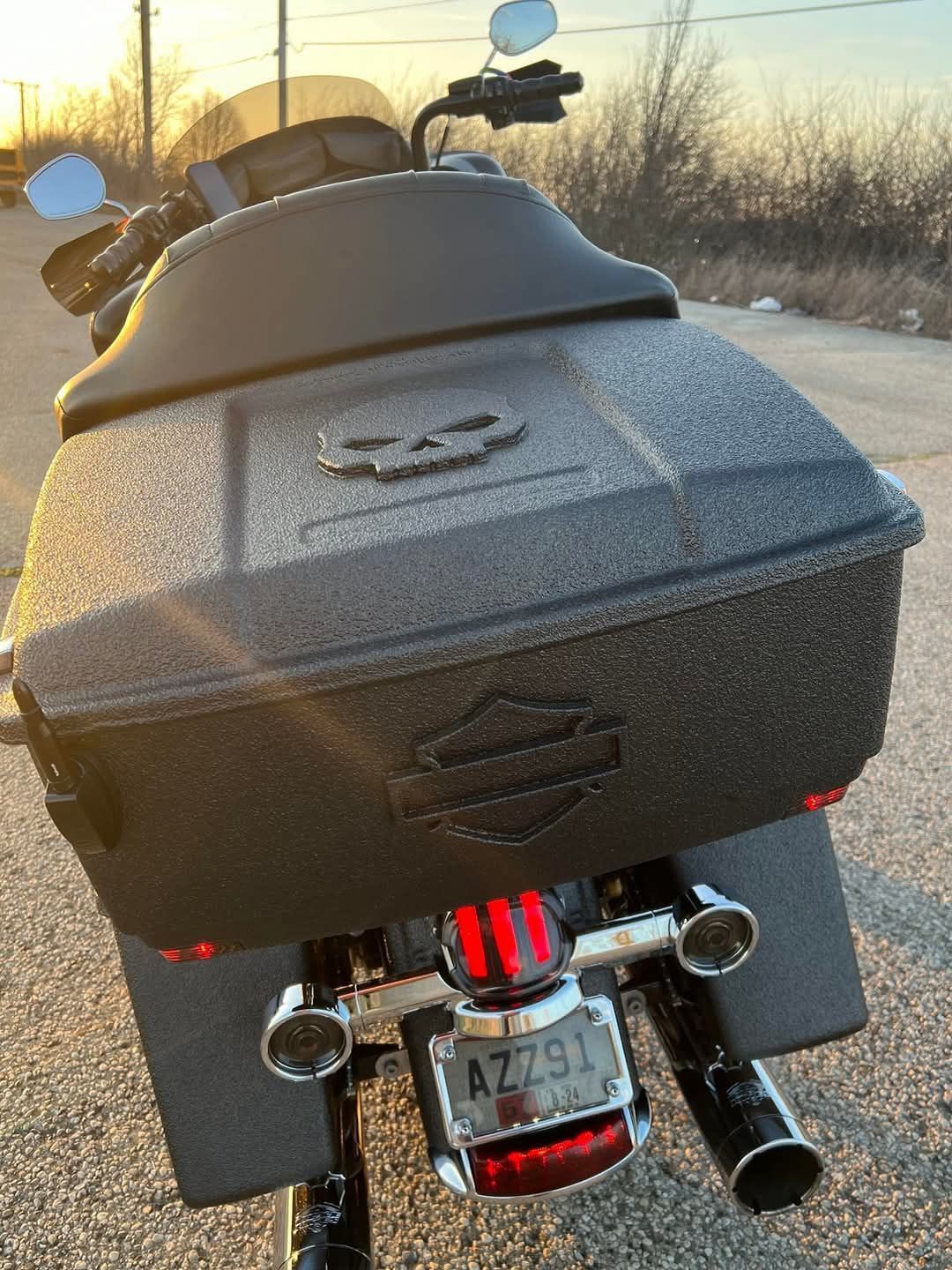 Black Harley-Davidson motorcycle, rear view. Black hard case luggage and exhaust. License plate, AZ791. Evening setting.