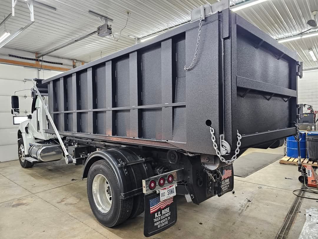 Black dump truck in a garage, angled rear view.