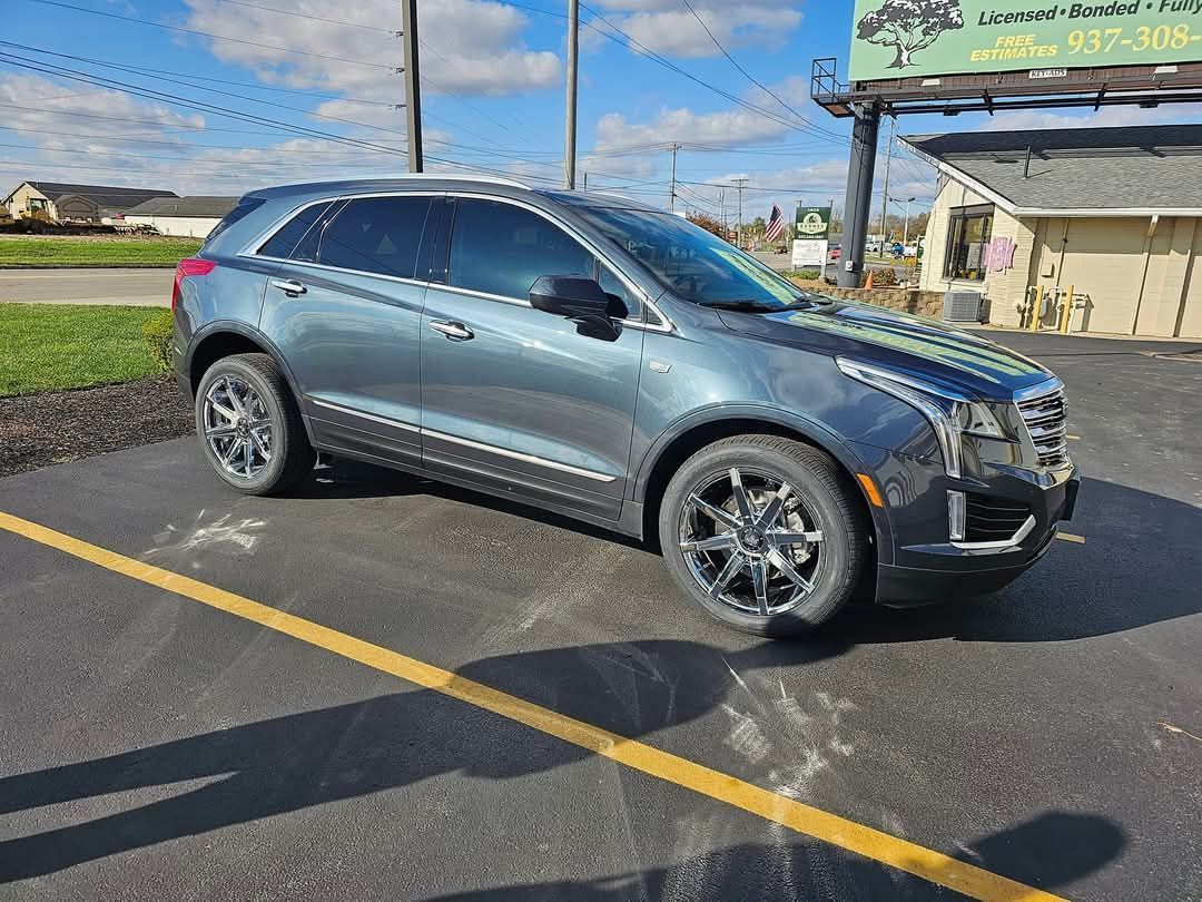 A gray Cadillac XT5 SUV parked on a sunny day with dark tinted windows.