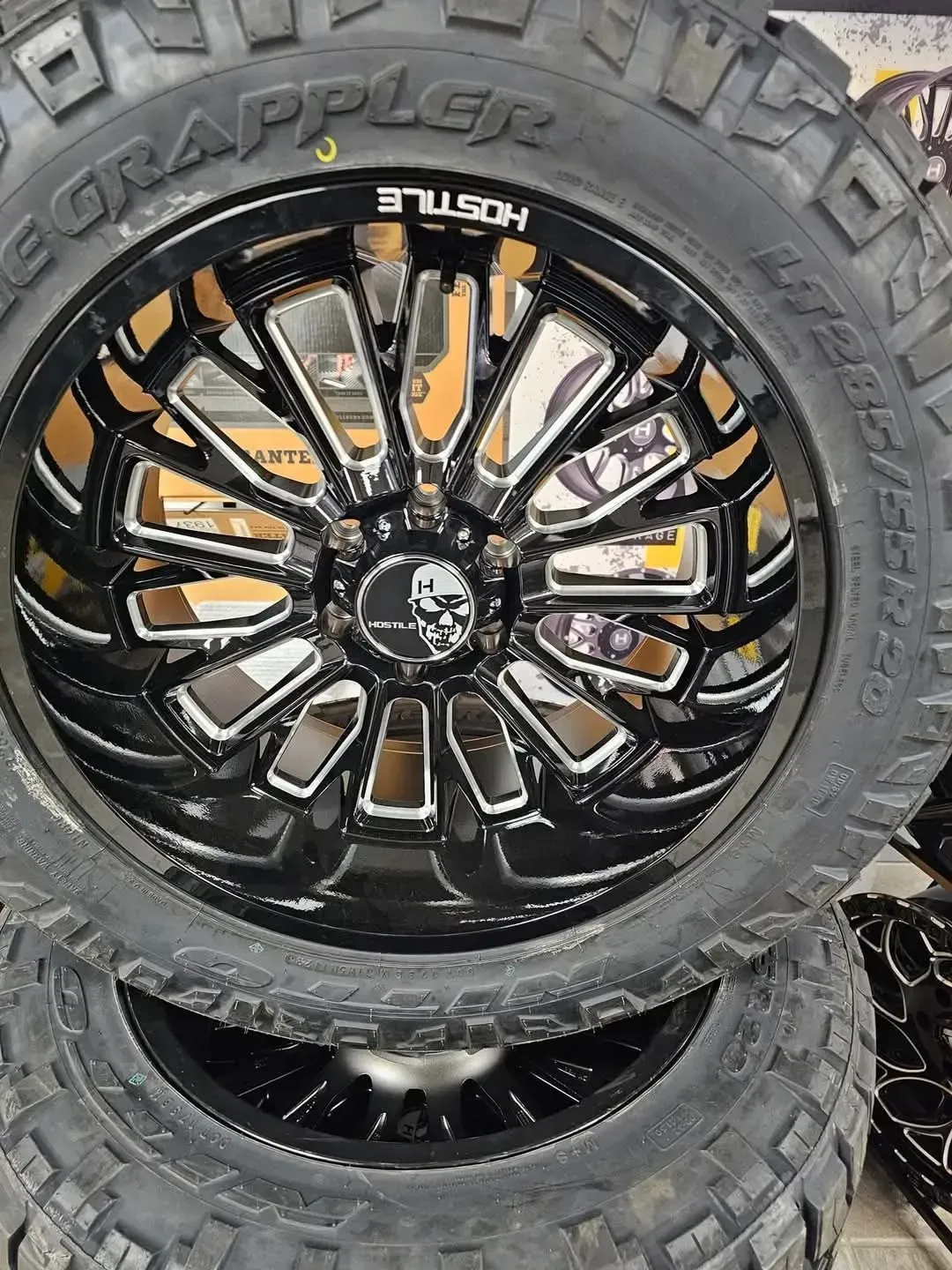 Black and chrome Hostile wheel with a skull logo, mounted on a tire.