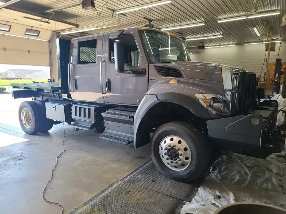 Gray truck cab in a garage; open bay door, concrete floor.