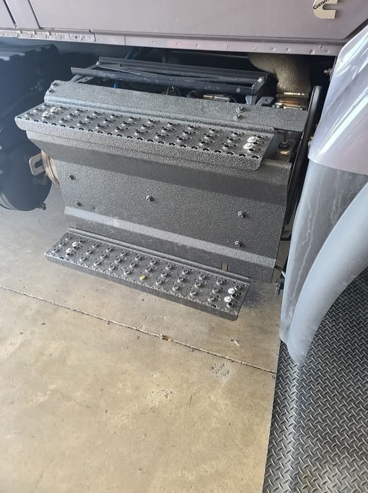 Gray truck steps, lower and upper levels, with textured non-slip surfaces.