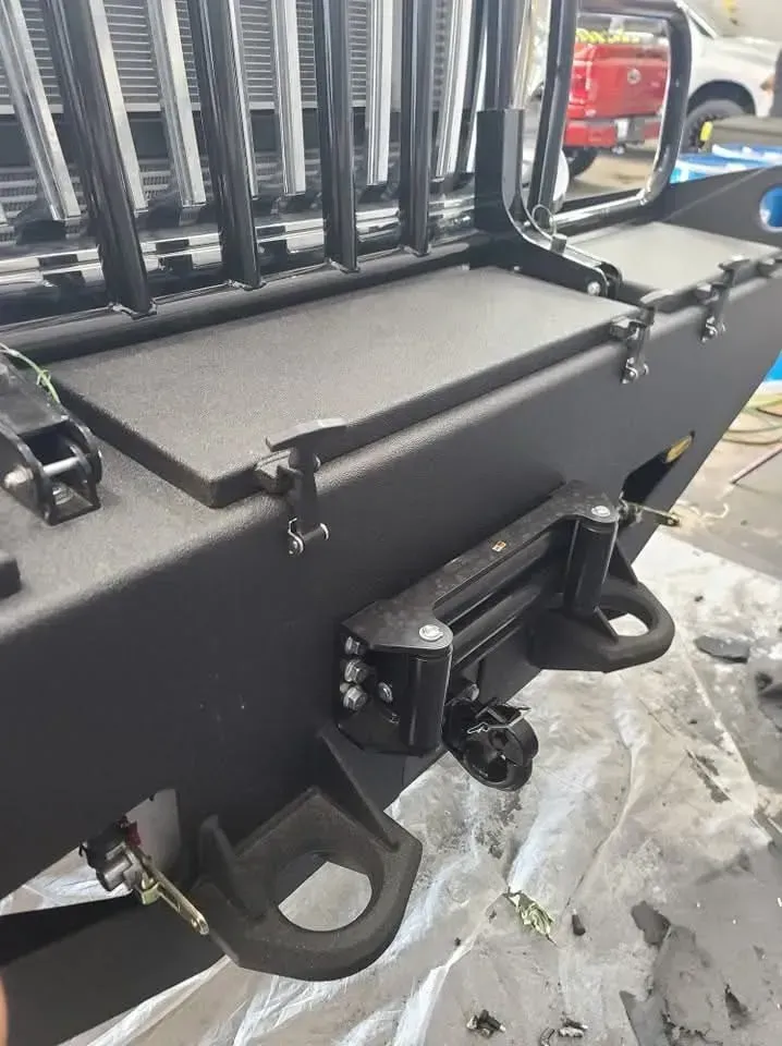 Black aftermarket car bumper with a winch and tow hooks.