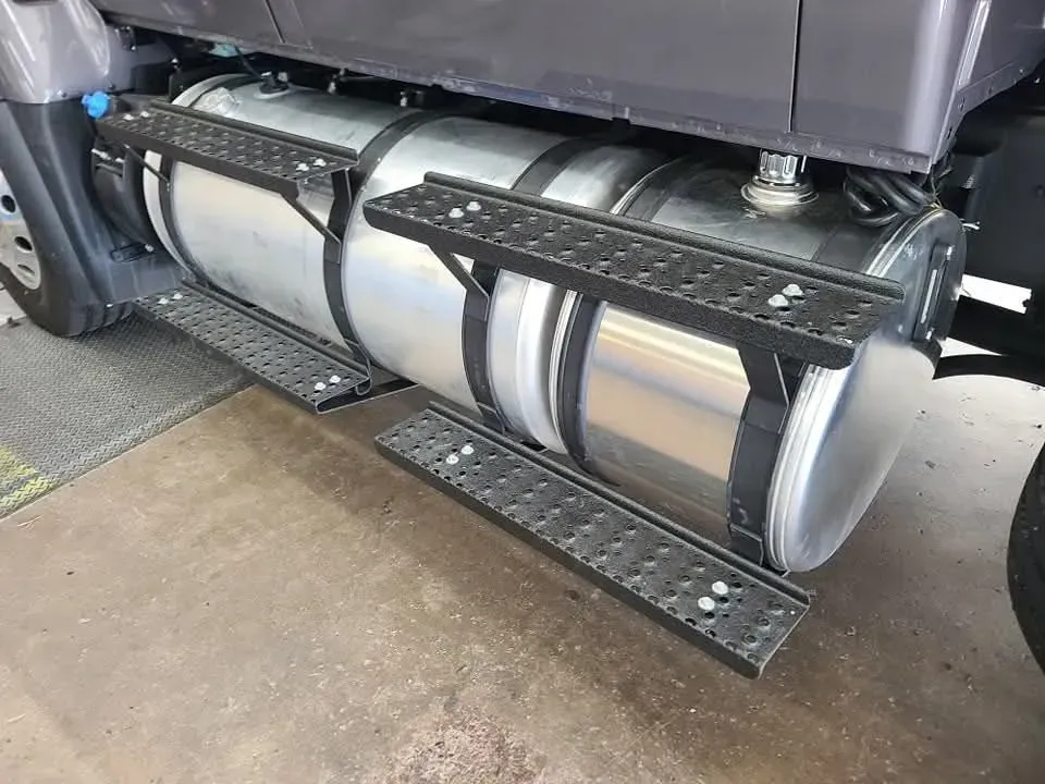 Fuel tank and steps on a commercial truck, silver tank with black steps and mounting brackets.