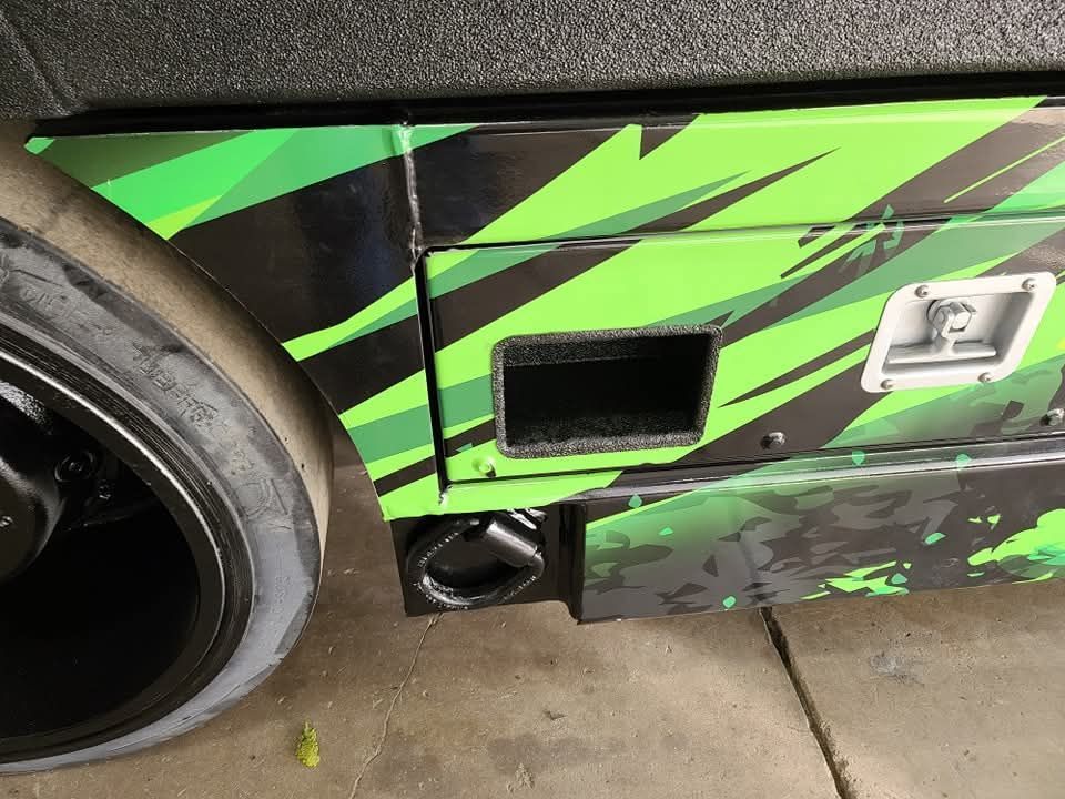 Black tire and green and black patterned storage compartment on a vehicle.