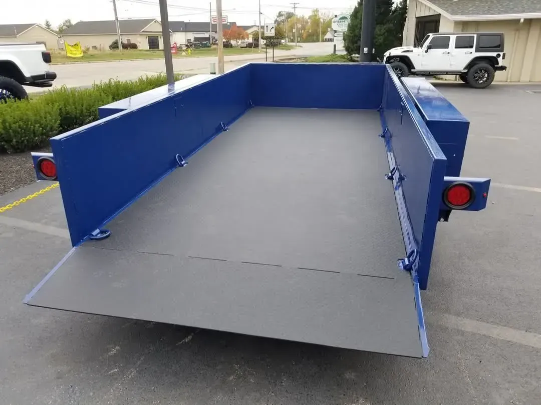 Blue utility trailer with a ramp in an outdoor setting.