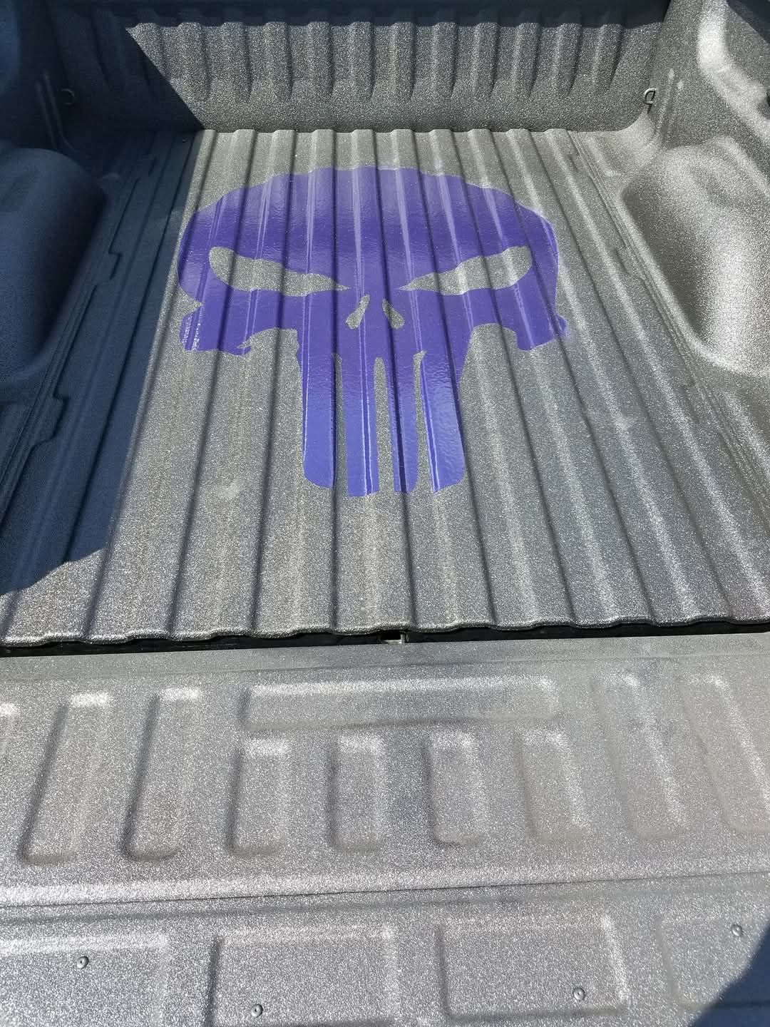 Purple Punisher skull painted on a truck bed.