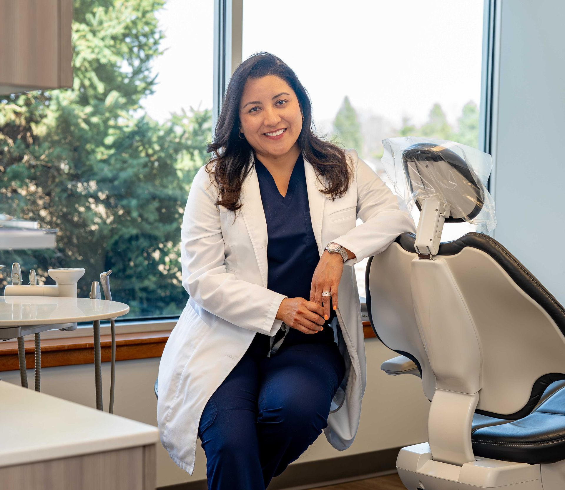 Smiling dental patient in a chair with a dentist holding a cup in a bright clinic