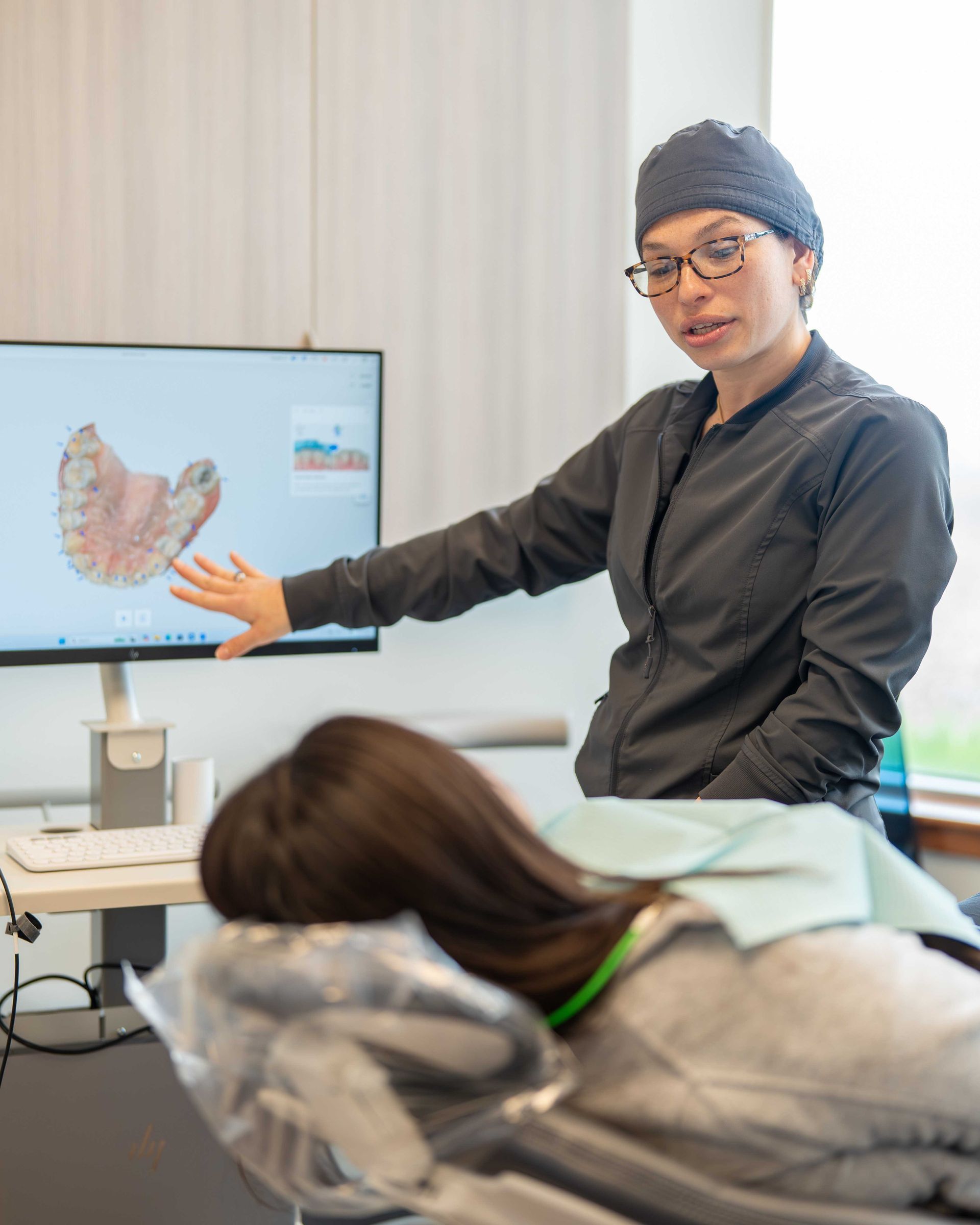 Instructor pointing at a screen showing a dental scan during a classroom lesson