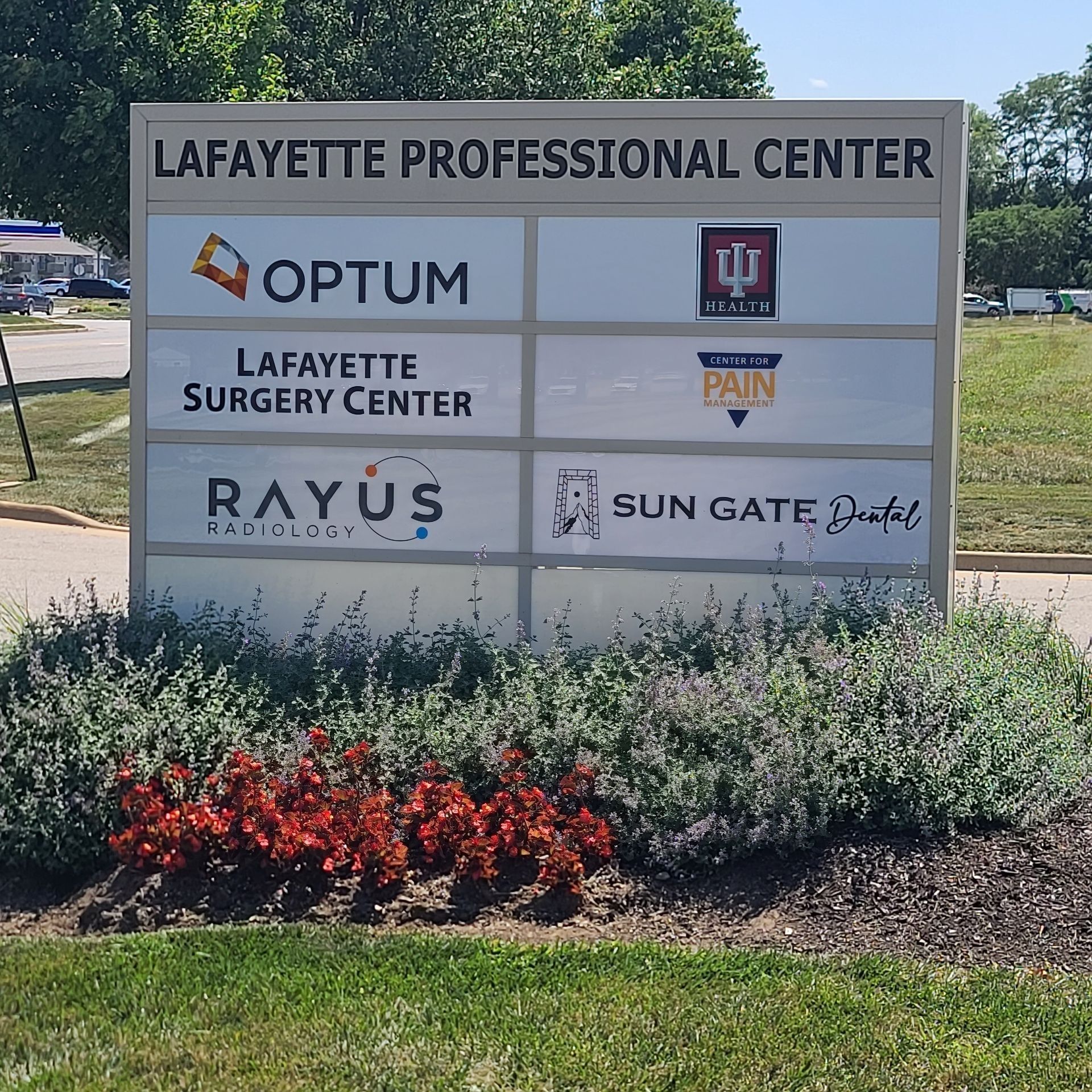 Lafayette Professional Center sign with business names, set beside a landscaped flower bed in sunlight