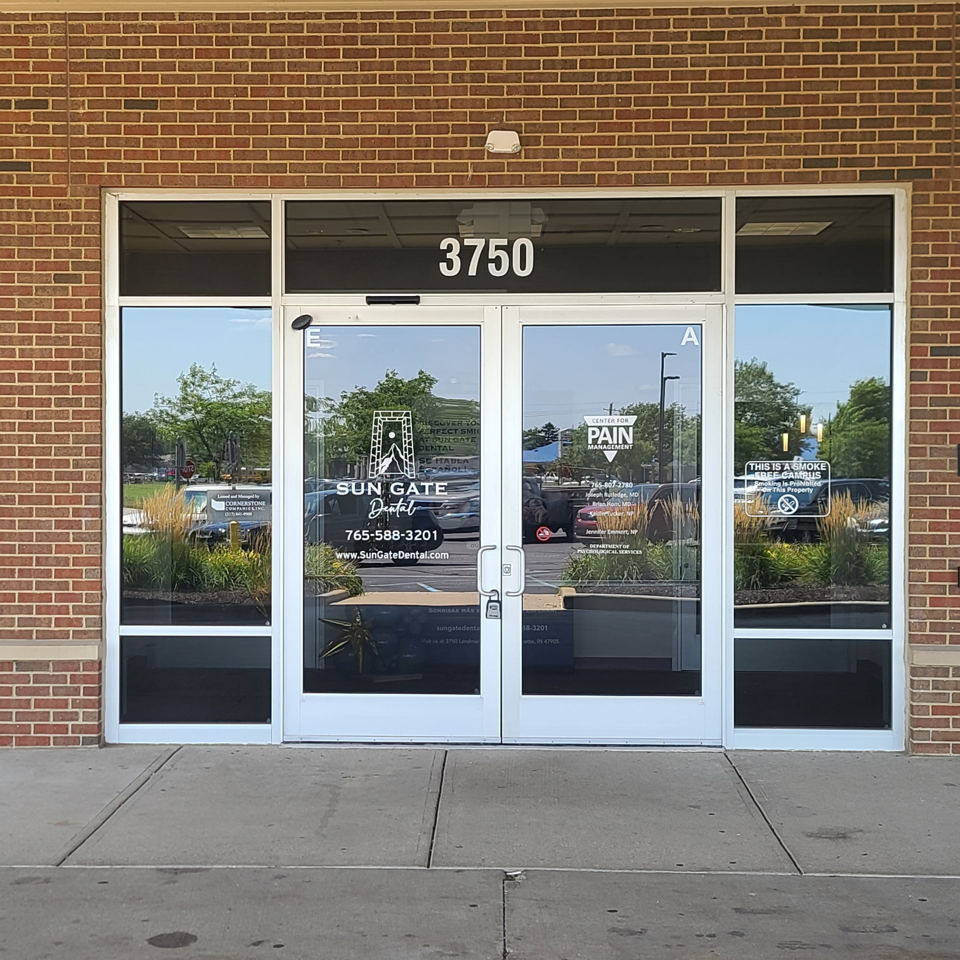 Brick storefront entrance with glass double doors and windows, address 3750 above the door