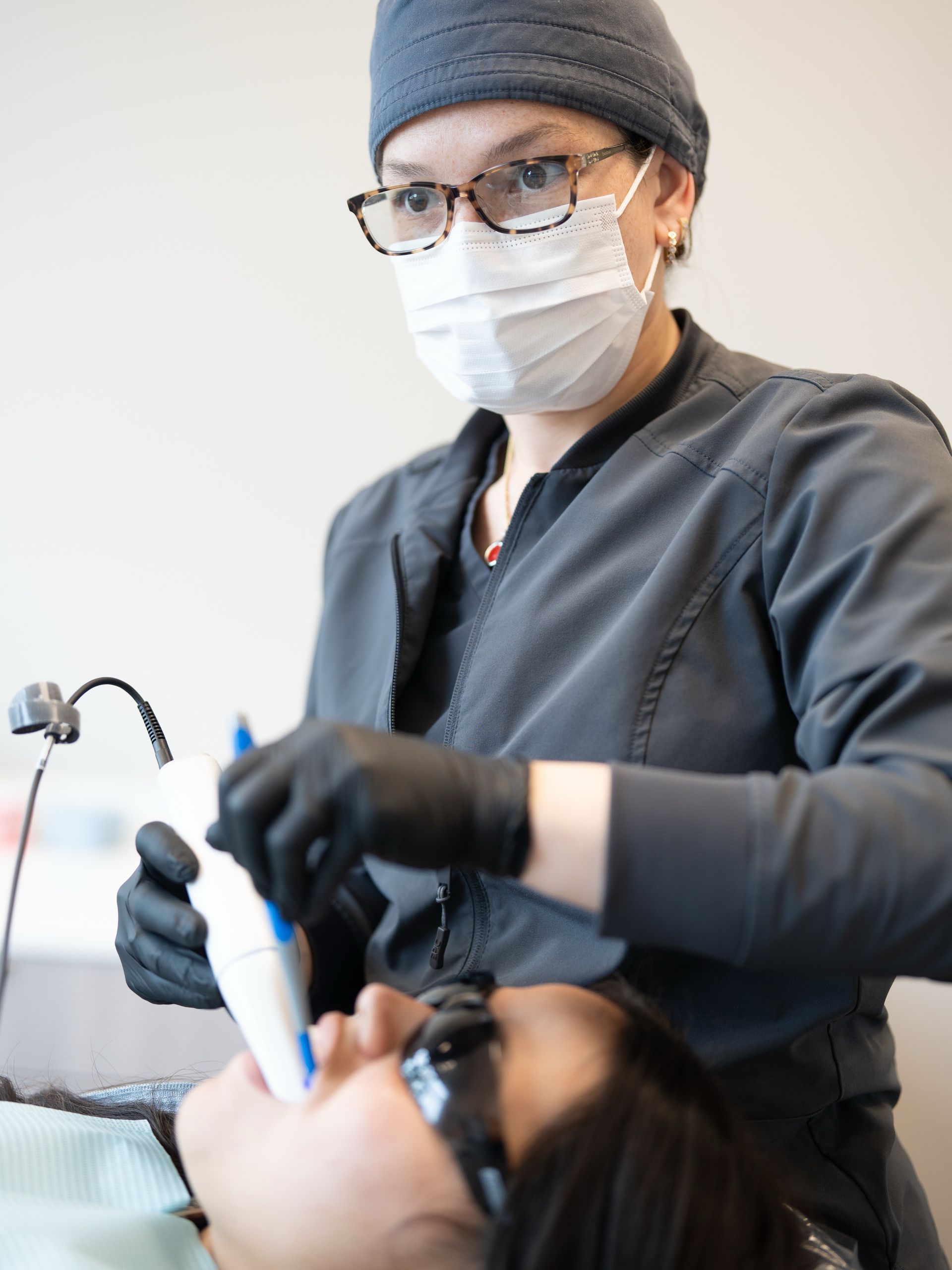 Dentist preparing a seated patient for treatment in a clinic, wearing gloves and a bib.