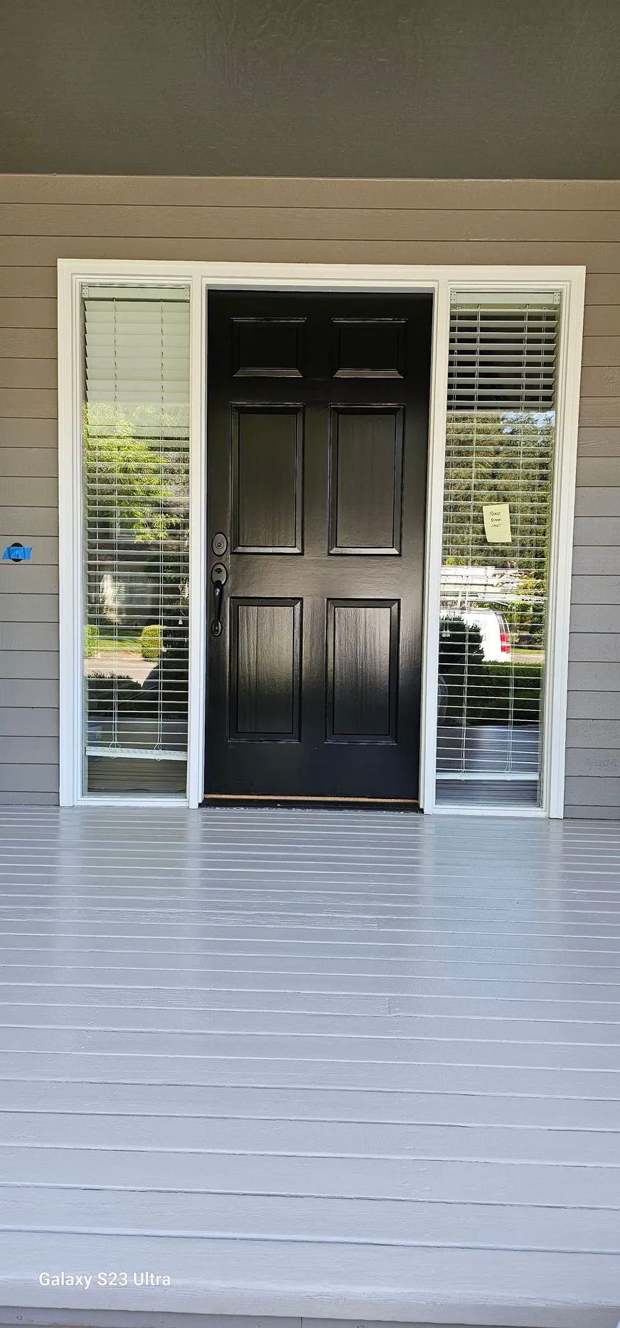 Front porch with black double doors and white sidelights under a covered entry.