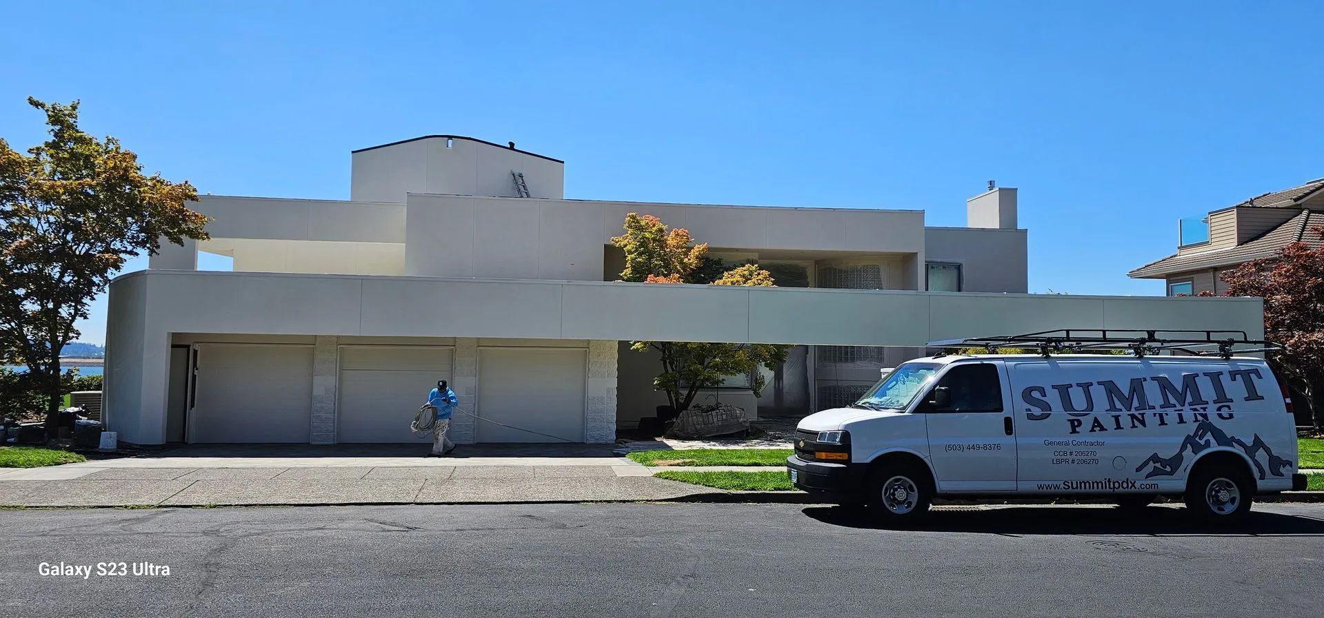 Modern white building with a van parked in front and a person near the entrance.