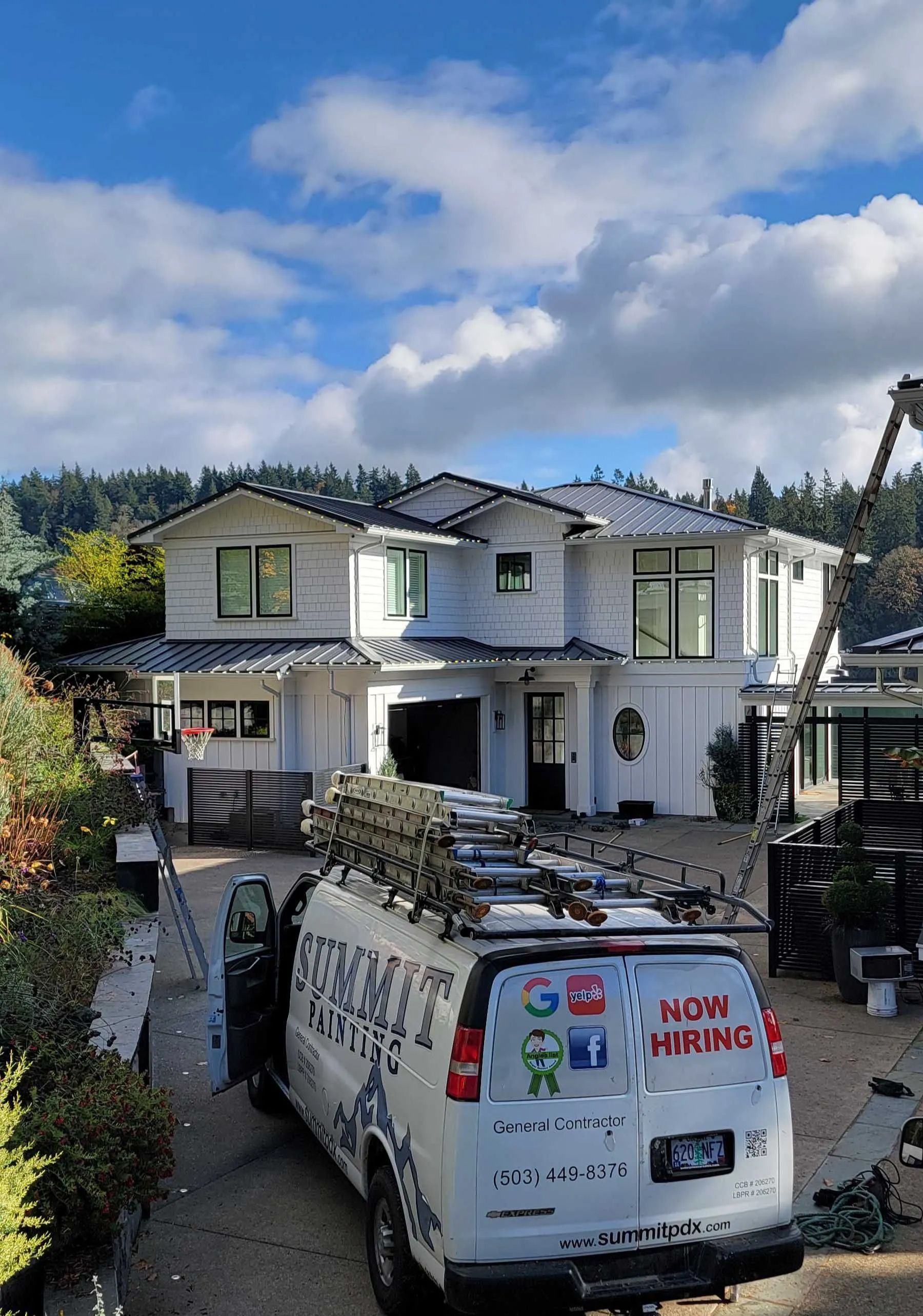 Two-story house with a white service van parked in front under a cloudy blue sky