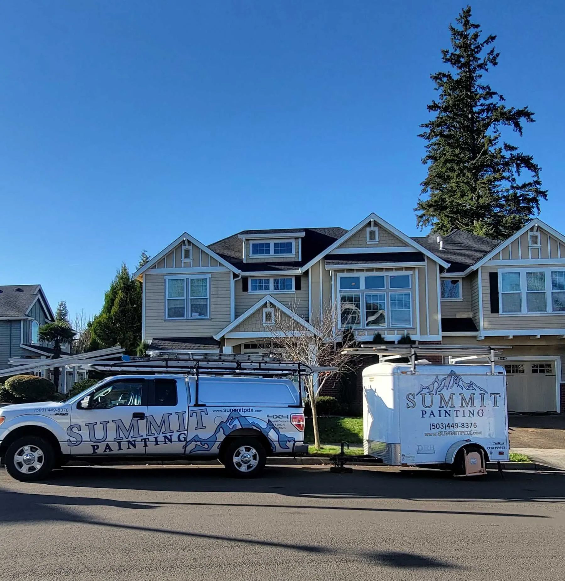 White service truck towing a trailer parked in front of a house on a sunny street