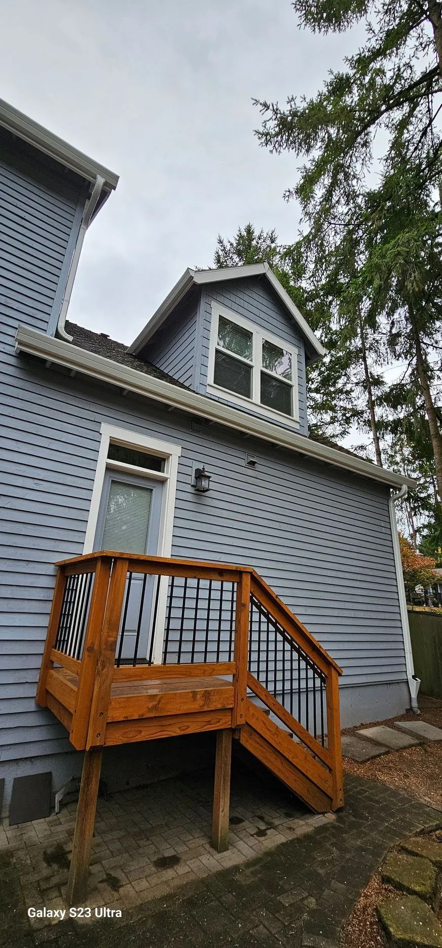 Gray house exterior with white trim and orange wooden porch stairs leading to a side door
