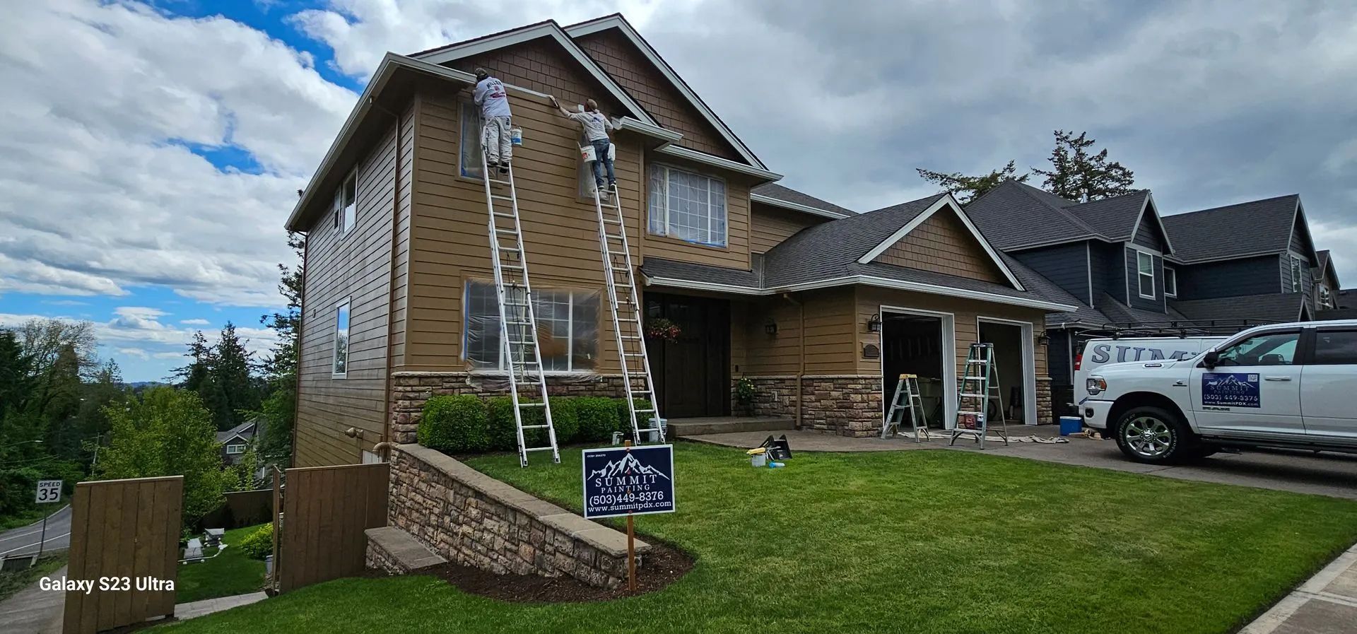 Suburban brick house under construction with a ladder, lawn sign, and parked pickup truck