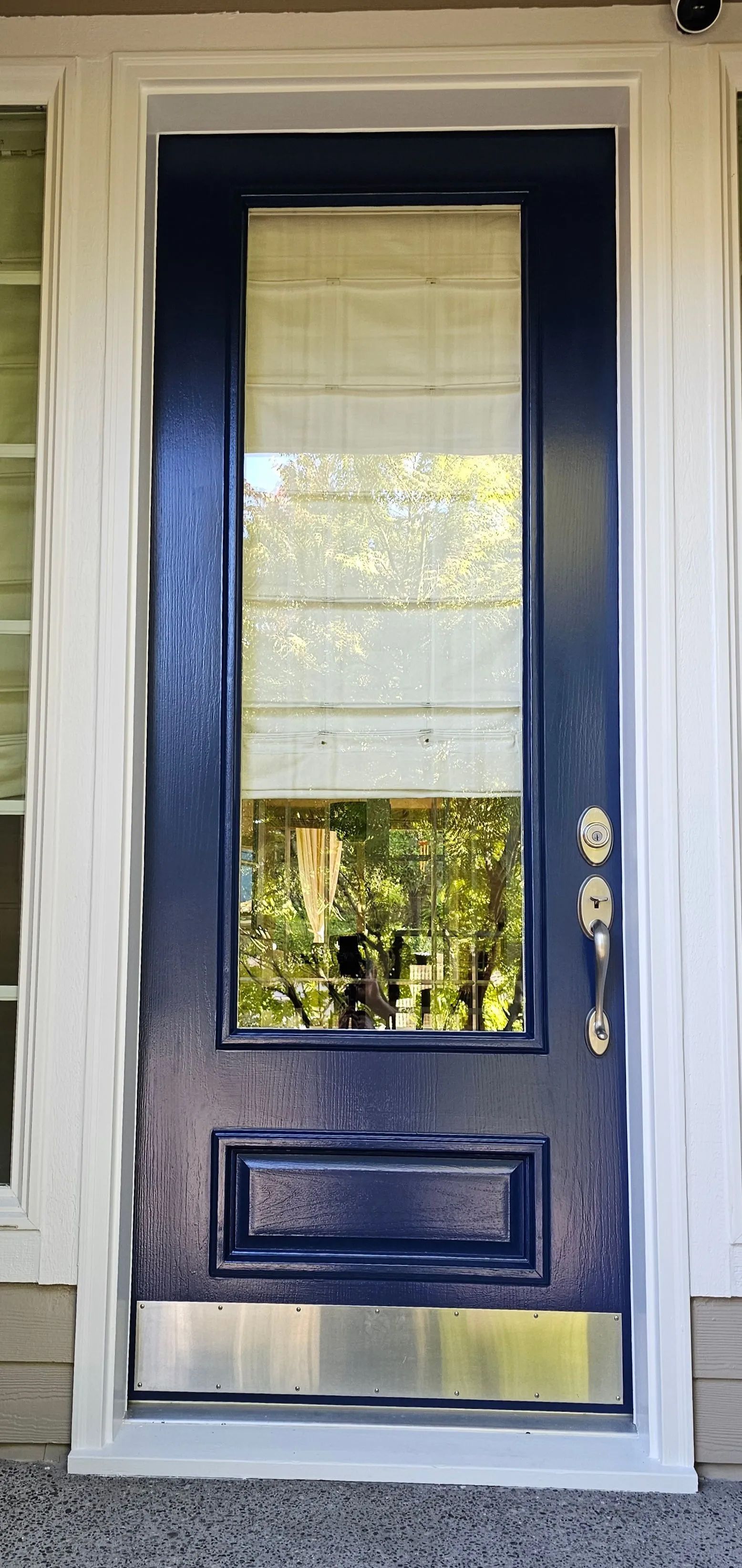 Blue front door with window panes and brass handle, framed by white trim and sidelights