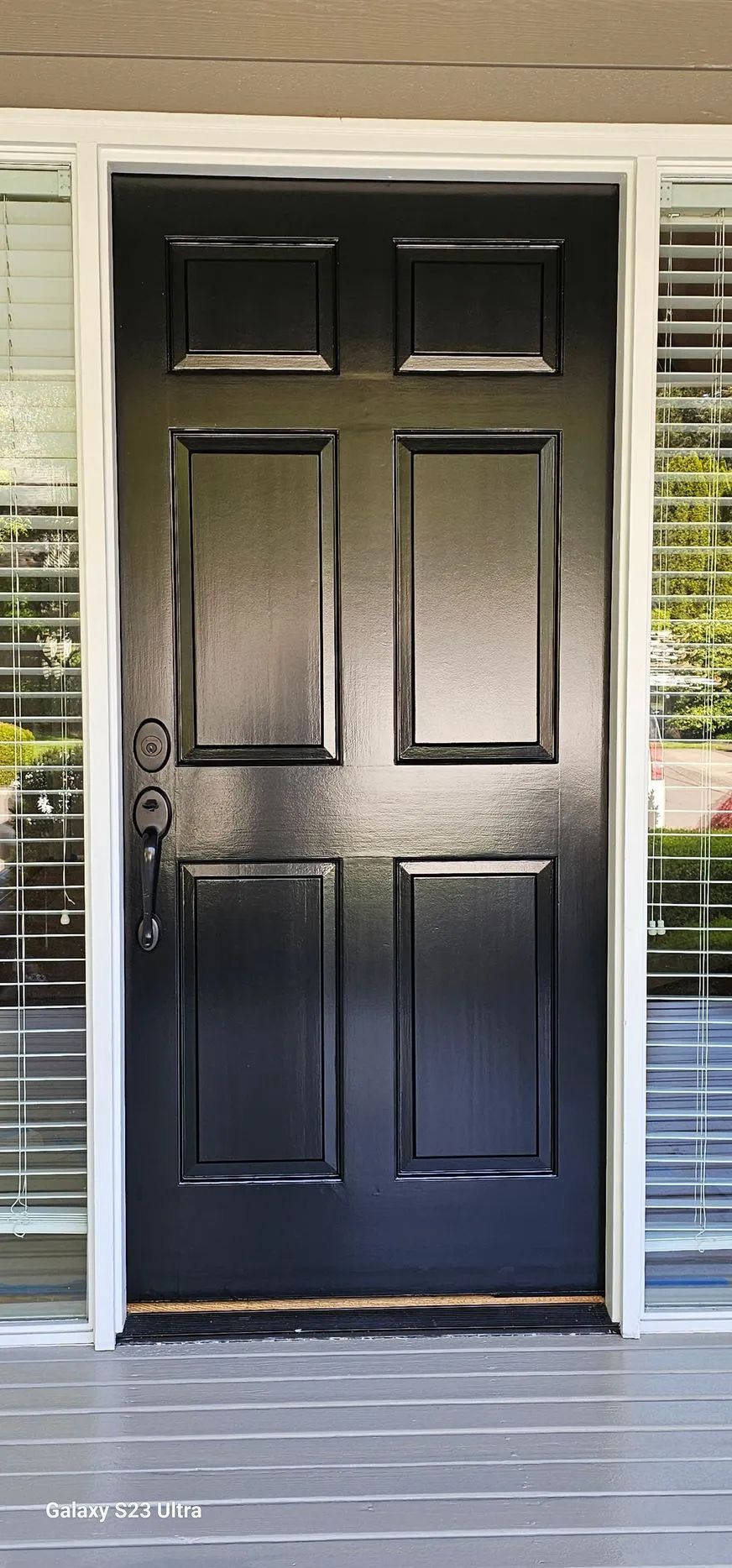 Black front door with white trim and sidelights on a porch
