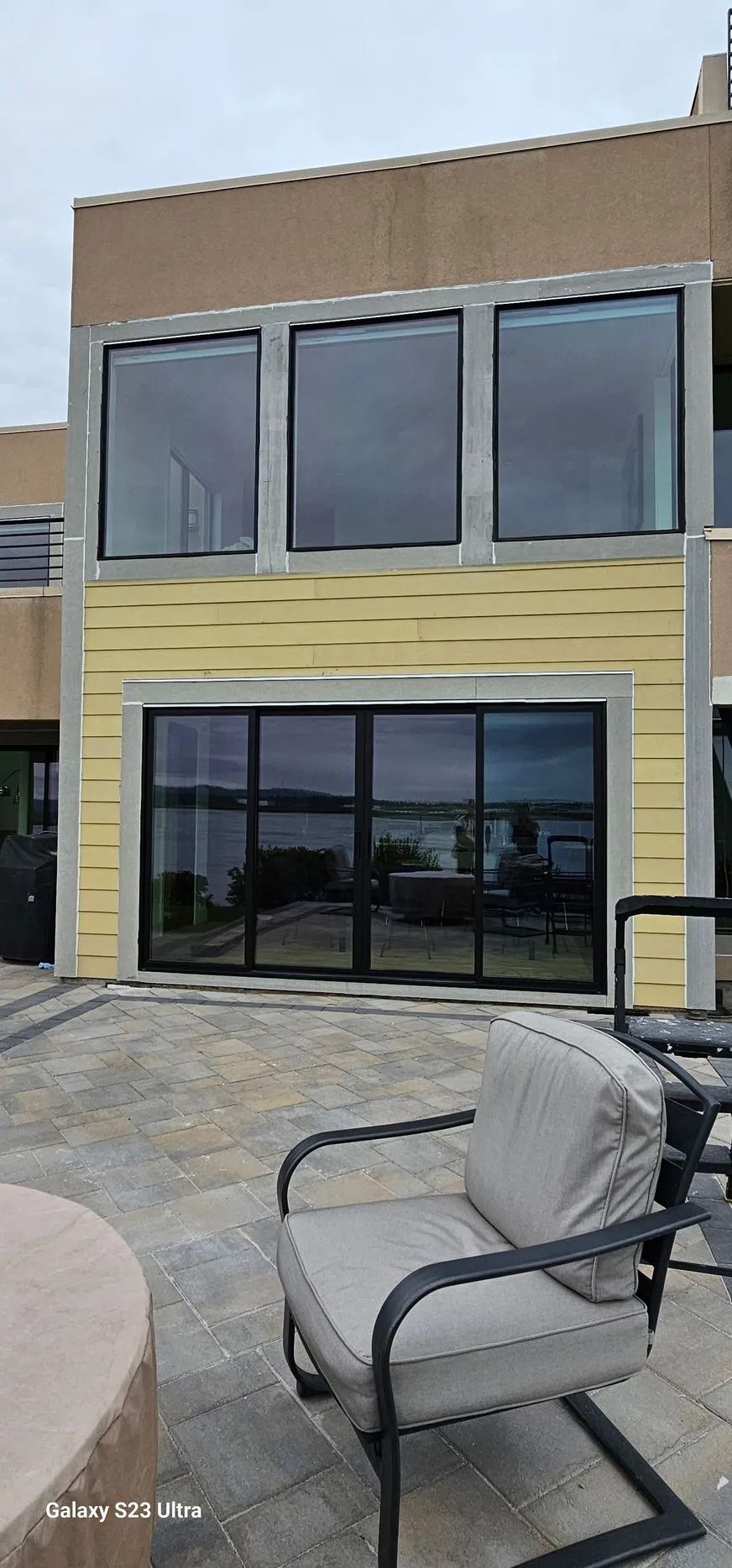 Modern two-story building with large windows and a patio chair in the foreground