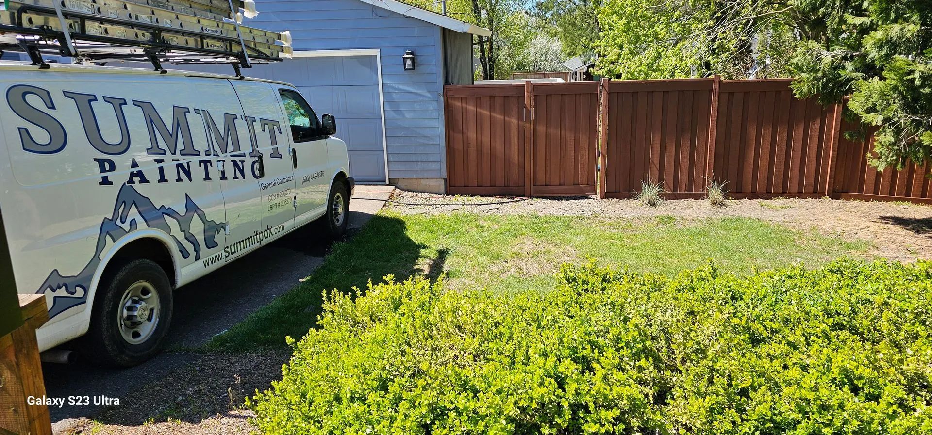Sunset Painting van parked by a wooden fence beside a green yard.