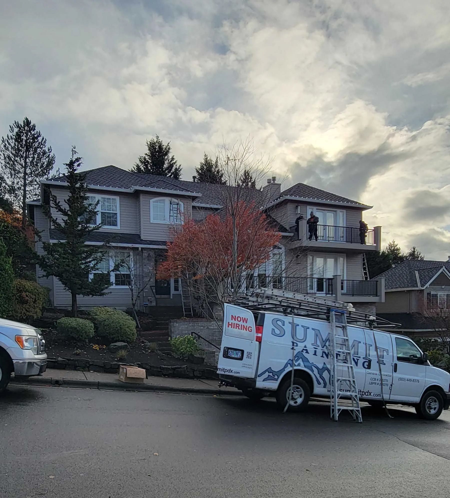 White utility van with signs parked on a suburban street in front of houses at dusk