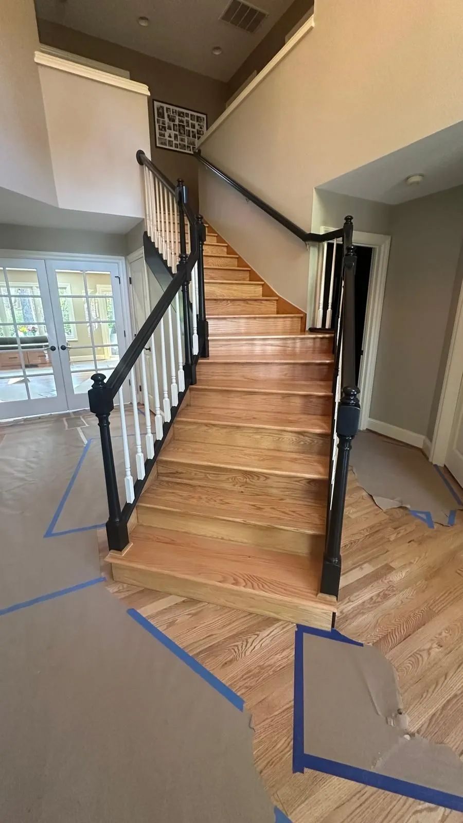 Interior wooden staircase with black railings in a partially renovated entryway