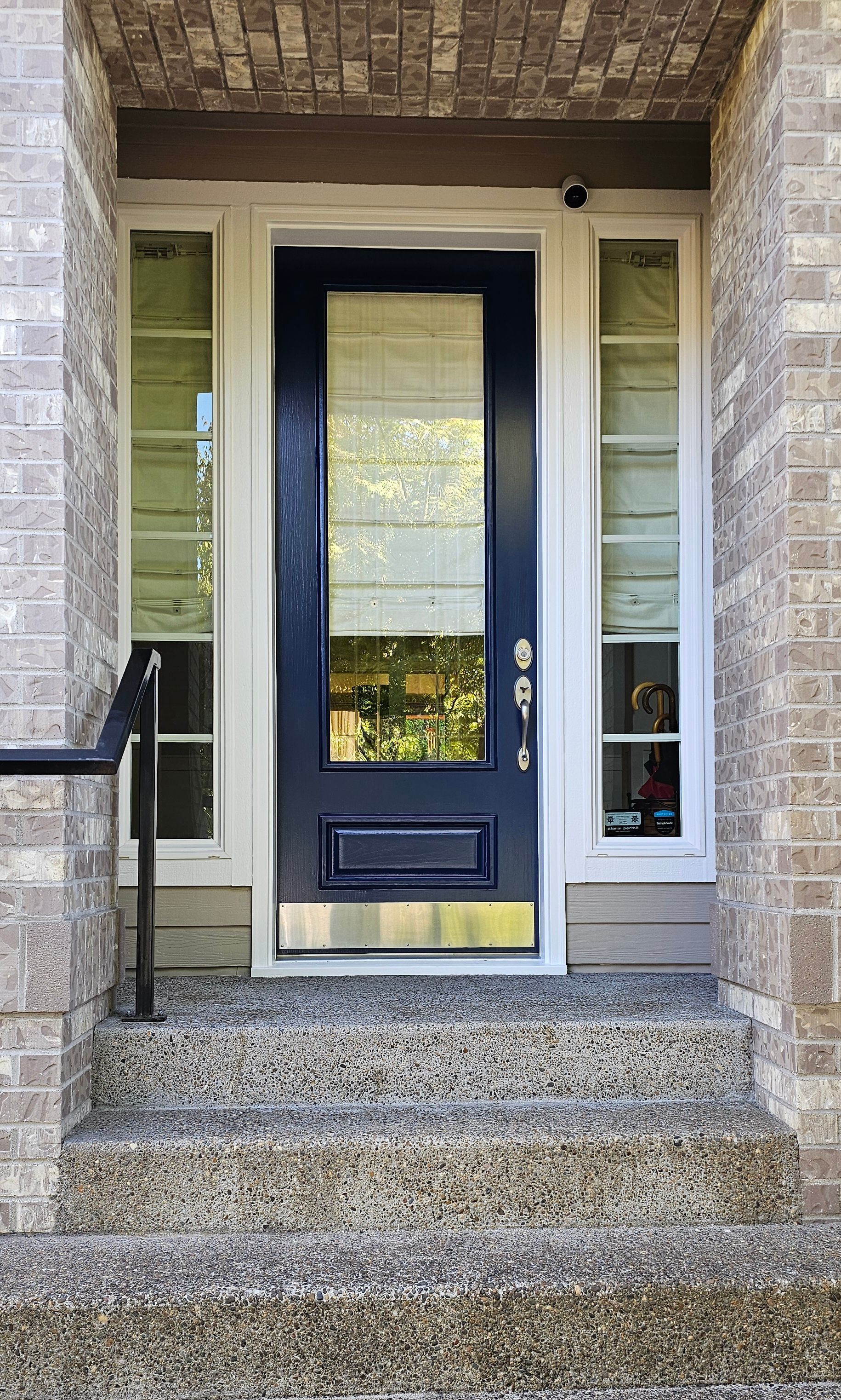 Front door with sidelights, steps, and brick facade. Navy blue door with brass accents.