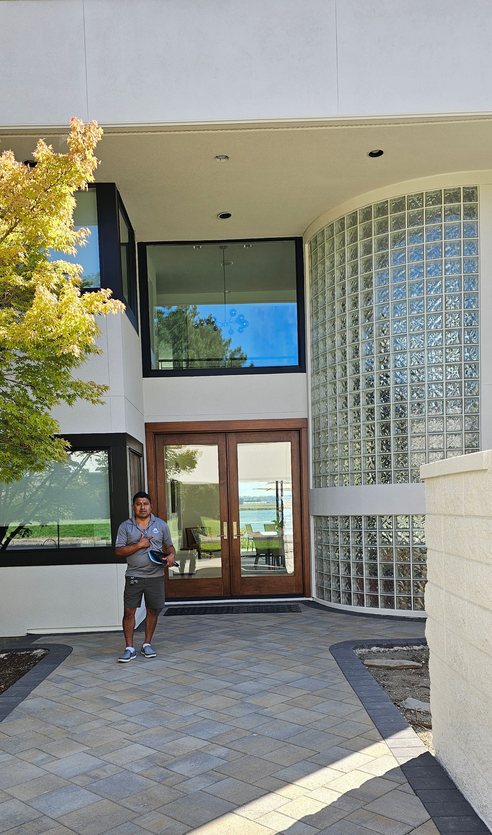 Man in front of a modern home with a glass block wall and wooden double doors.