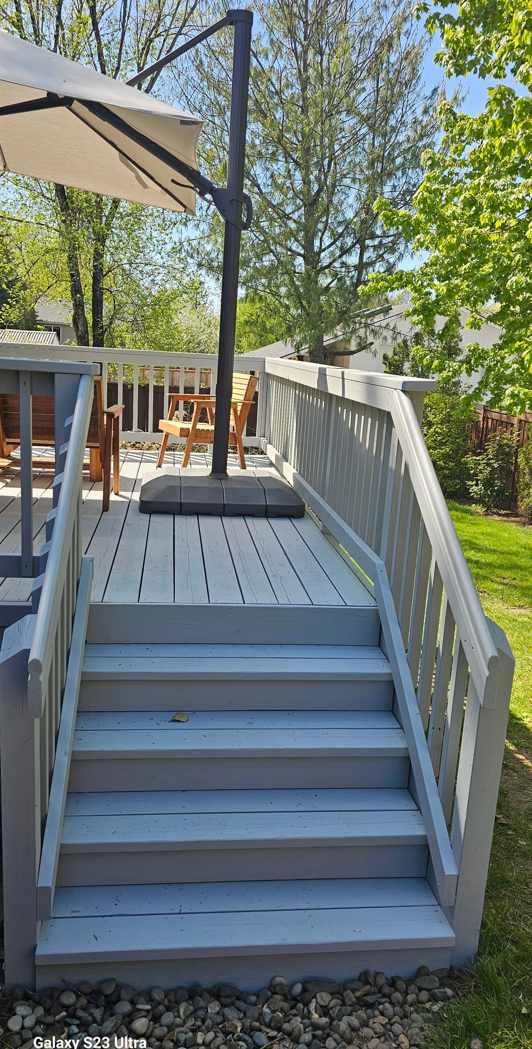Wooden deck with stairs, gray railing, and a large umbrella.