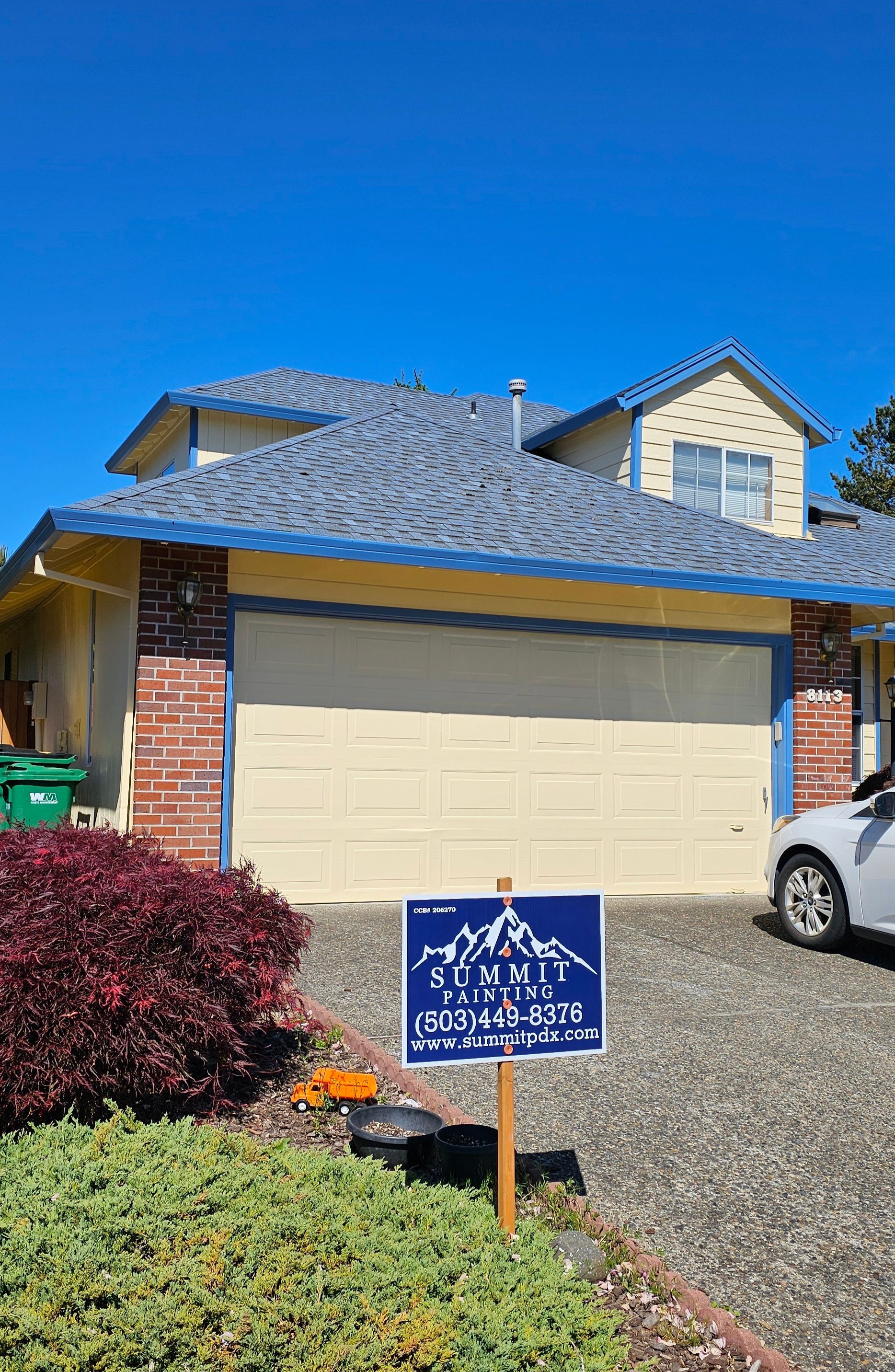 House with blue roof, garage, and a sign with mountain logo.