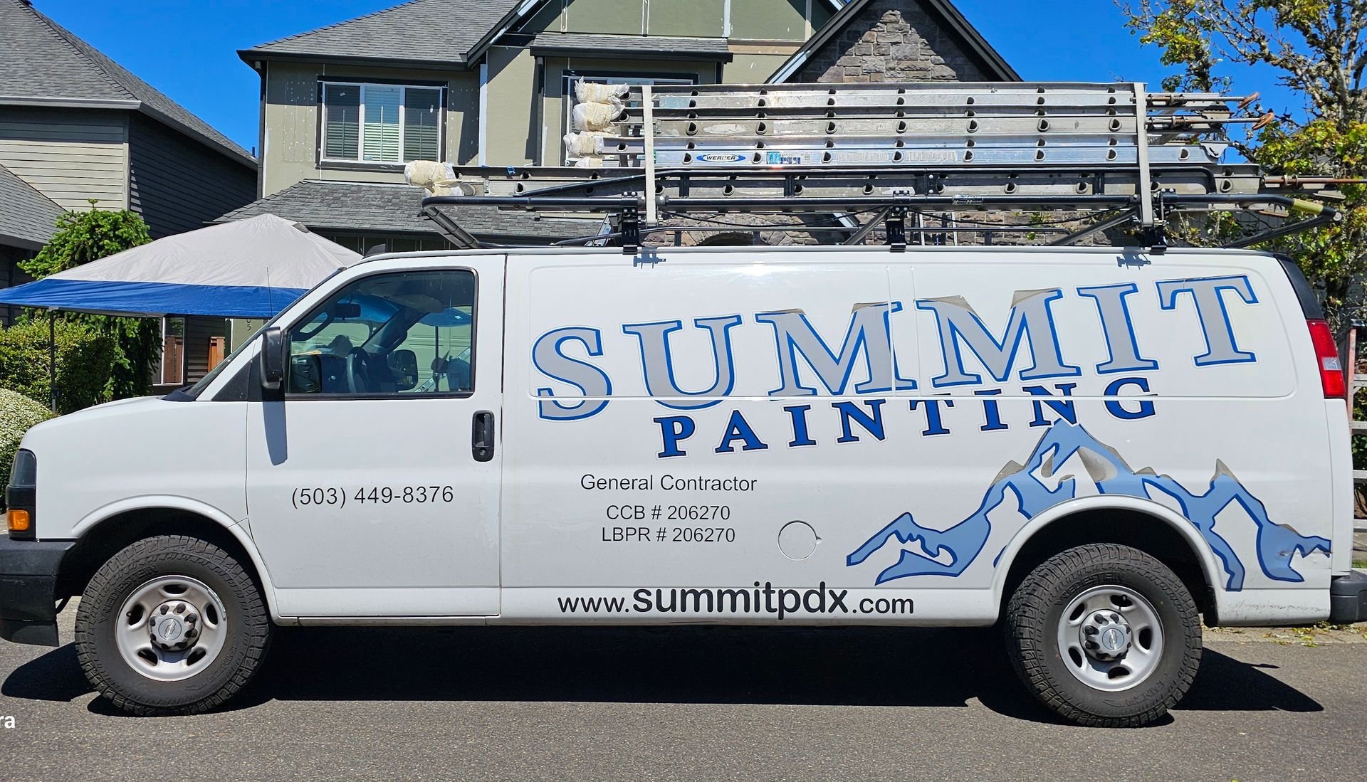 White Summit Painting van with a ladder on top, parked on a street in front of a house.