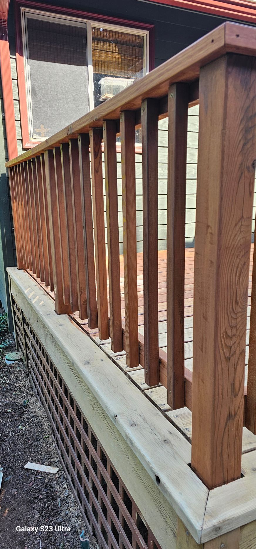 Wooden deck railing with vertical balusters. Brown wood, wire inserts, and light-colored trim.