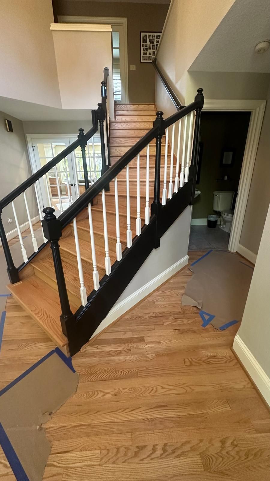 Wooden staircase with black railing and white spindles, leading up to a second floor.