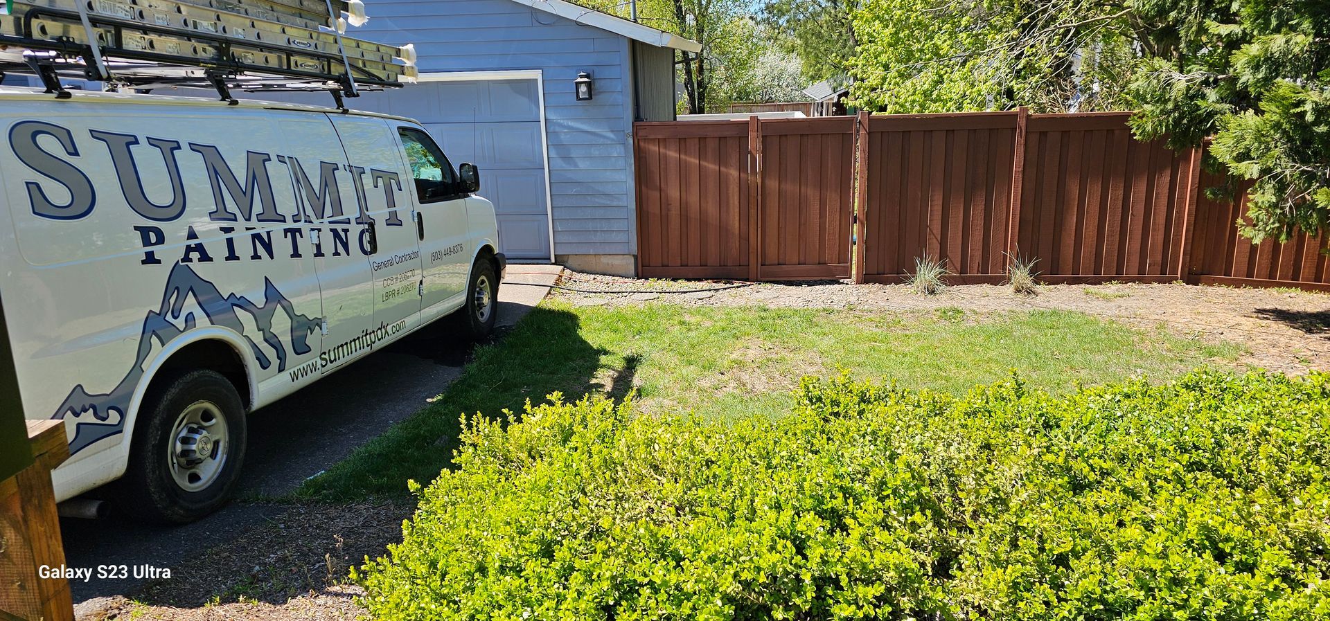 Summit Painting van parked near a brown fence and a garage, sunny day.