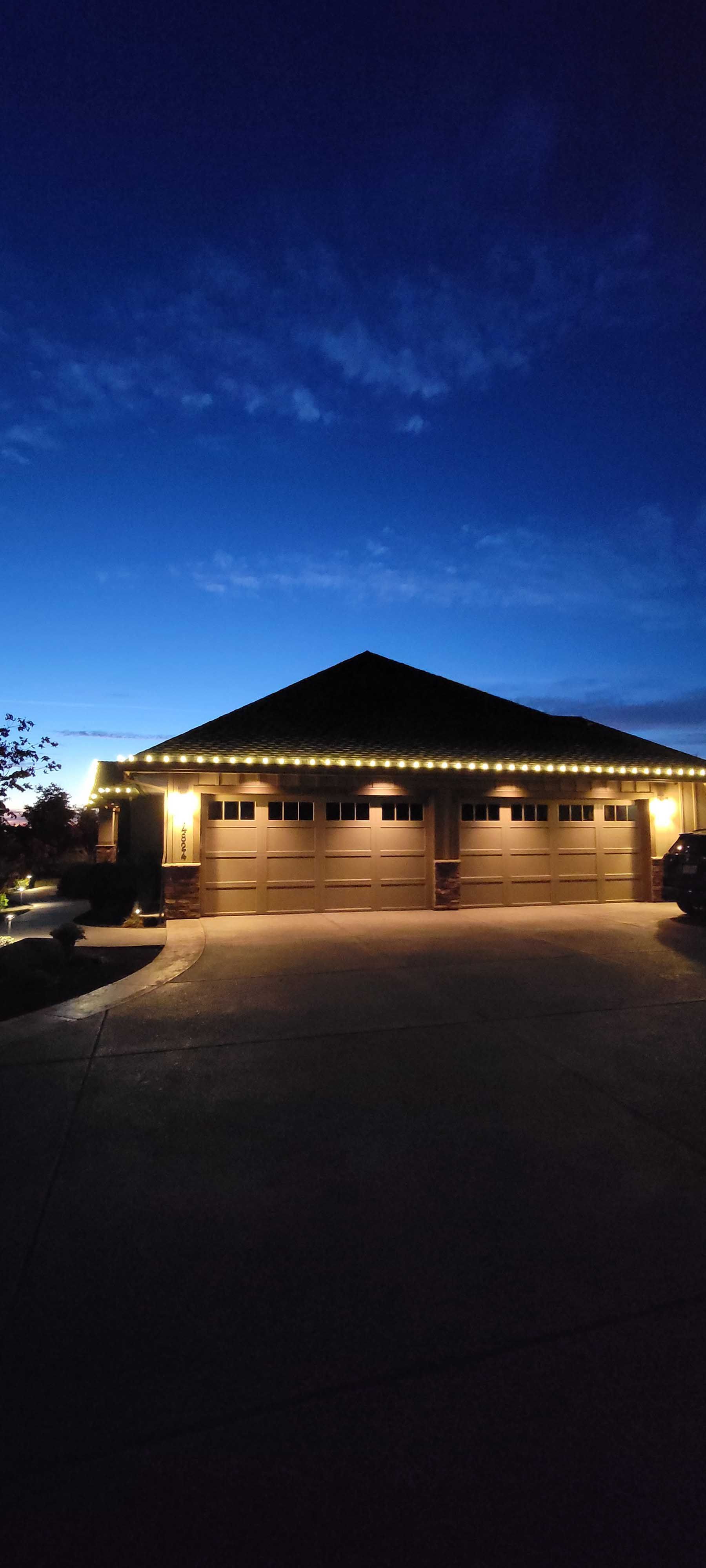 Garage with lit lights at dusk. Dark blue sky above.