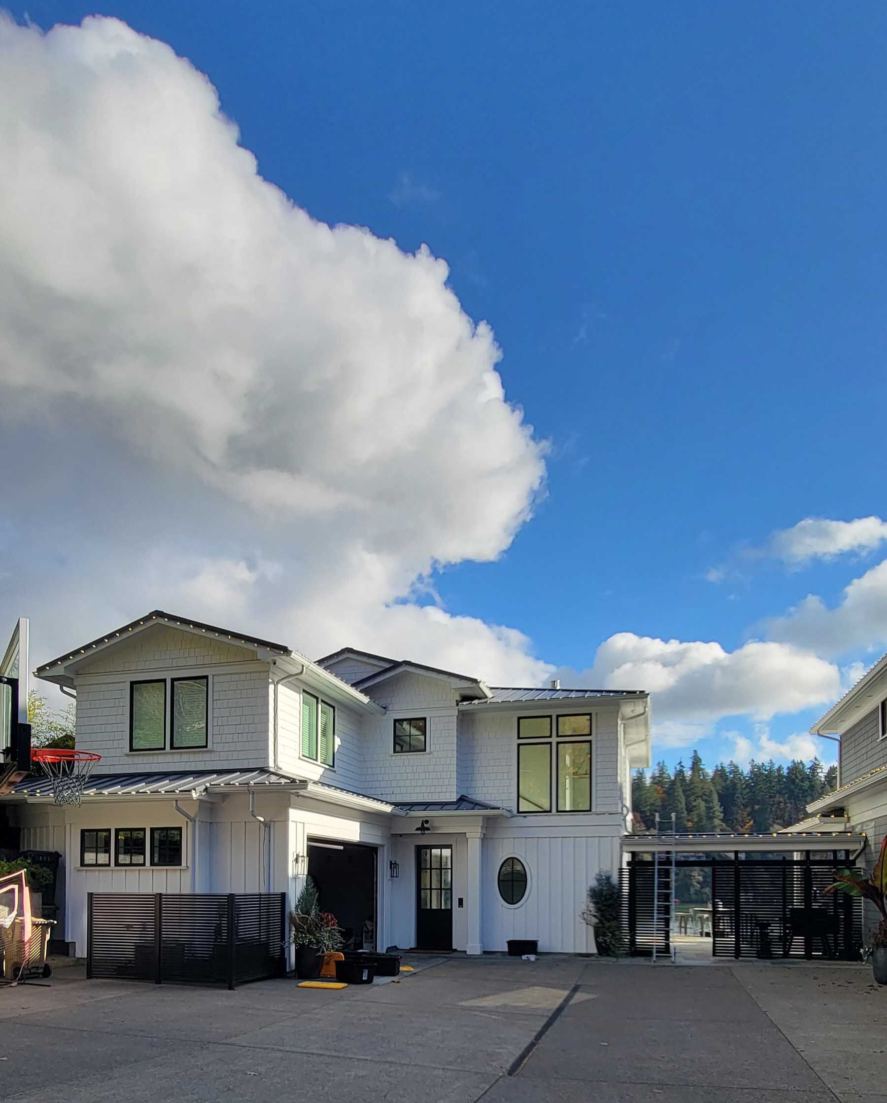 White house with black accents under a blue sky with fluffy clouds.