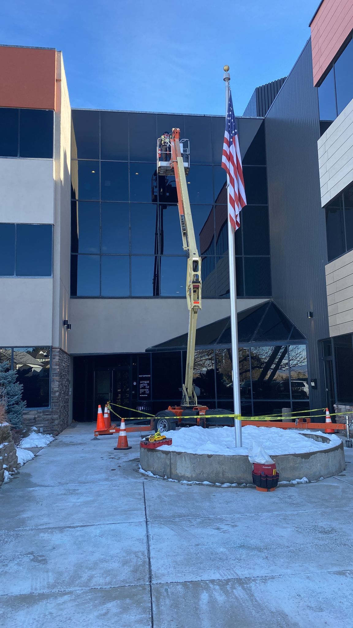 Person in lift working on building windows; American flag.