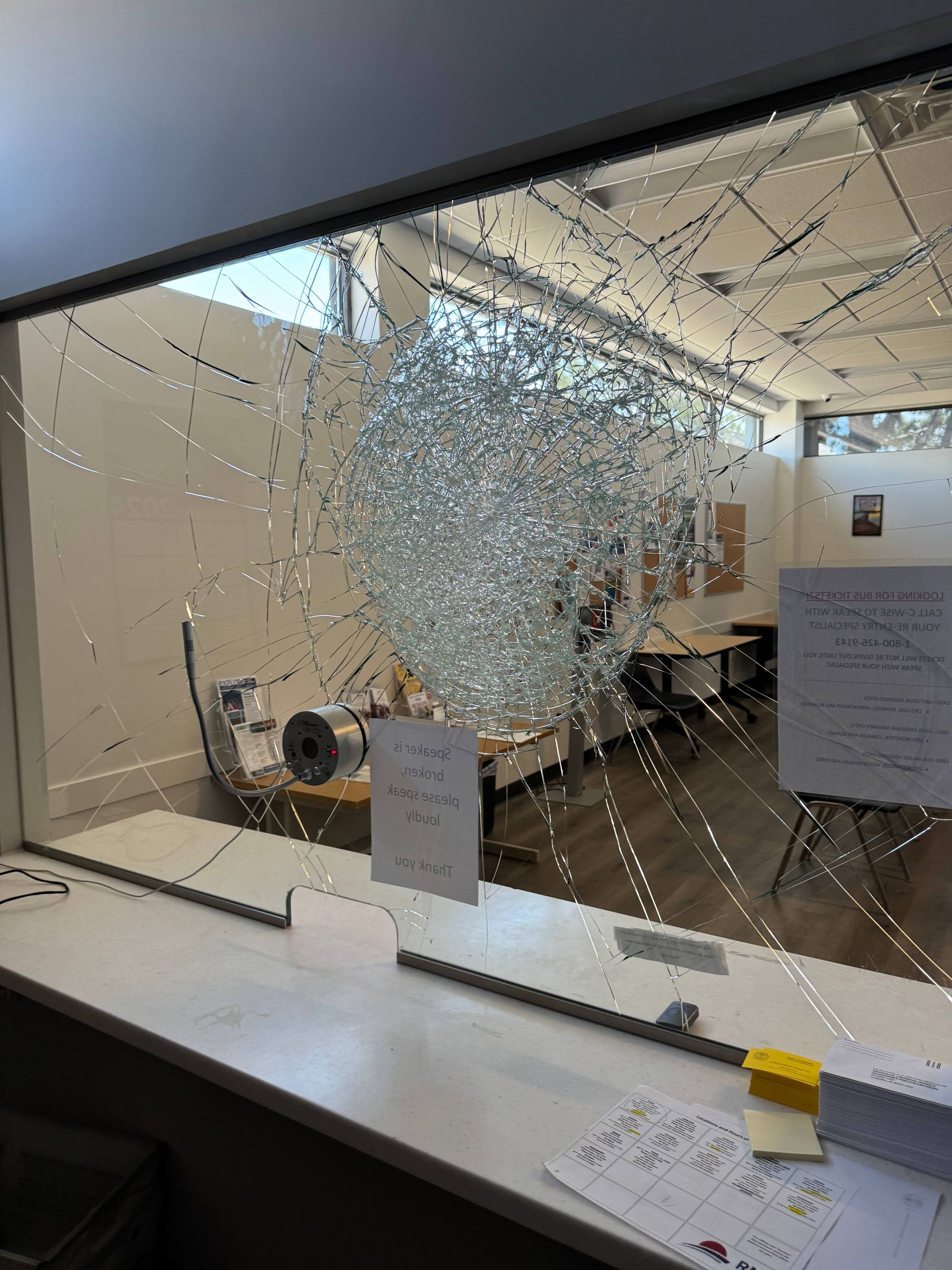Shattered glass window, showing a hole, in what appears to be an office or classroom.