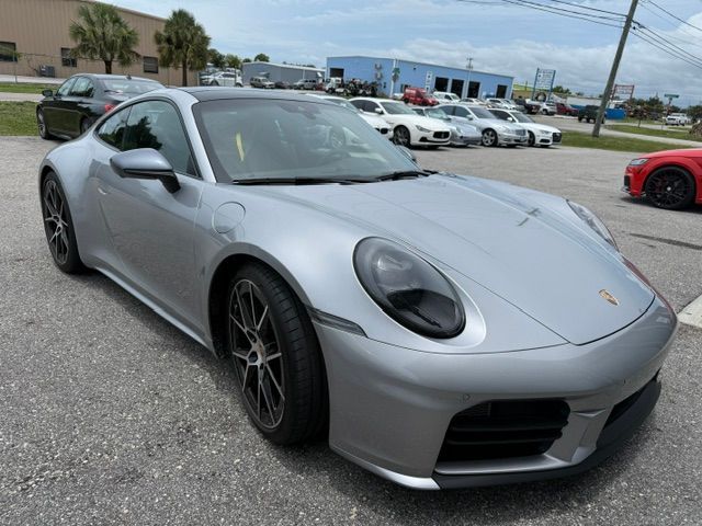Silver Porsche sports car parked outdoors on a lot, front-left view