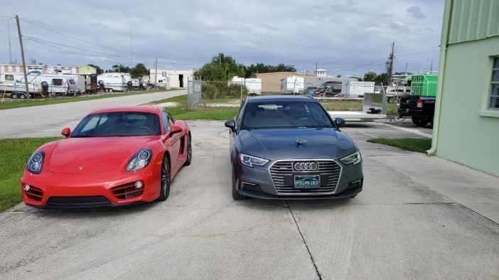 Two cars are parked next to each other in a driveway.