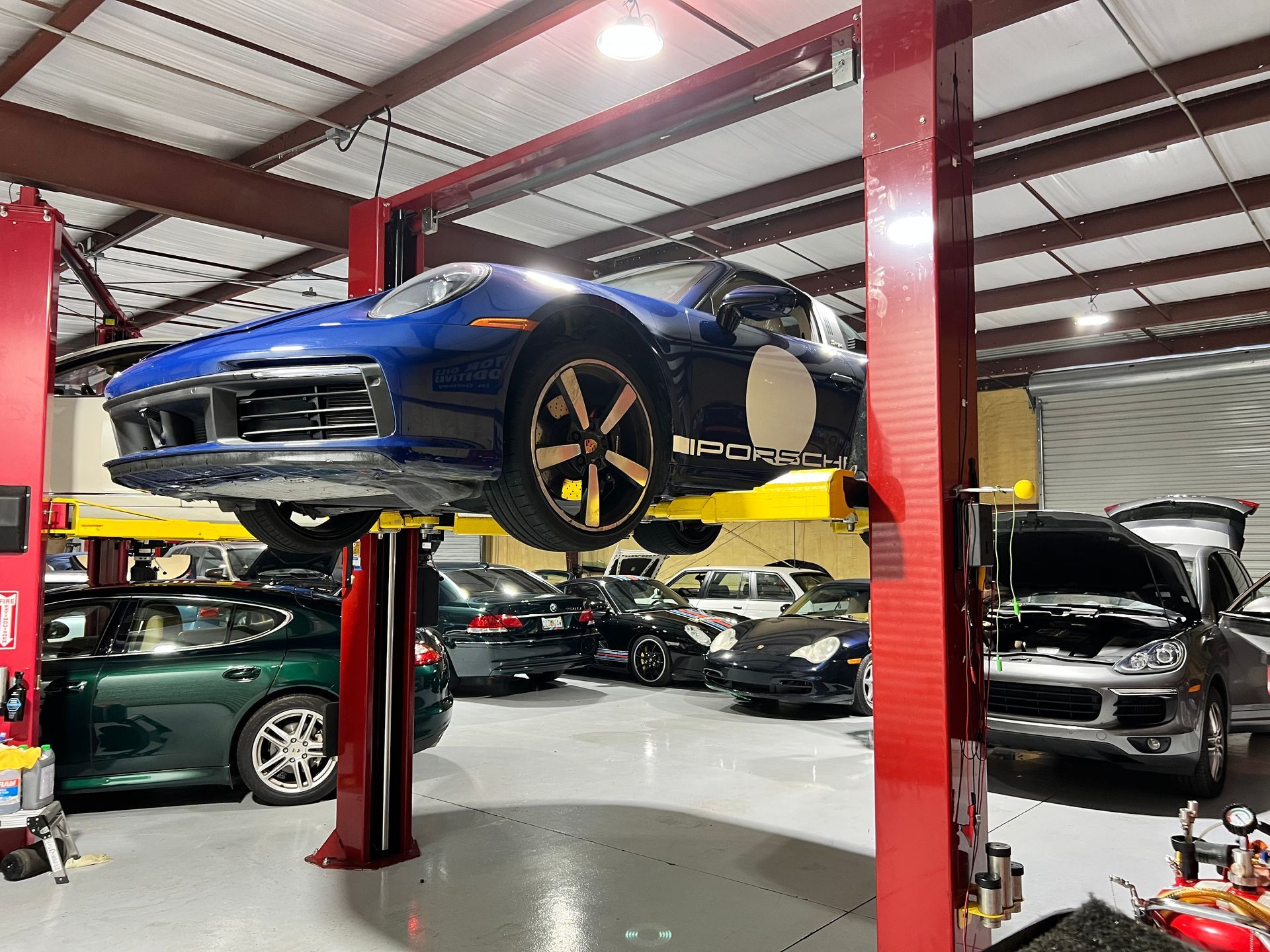 A blue car is on a lift in a garage.