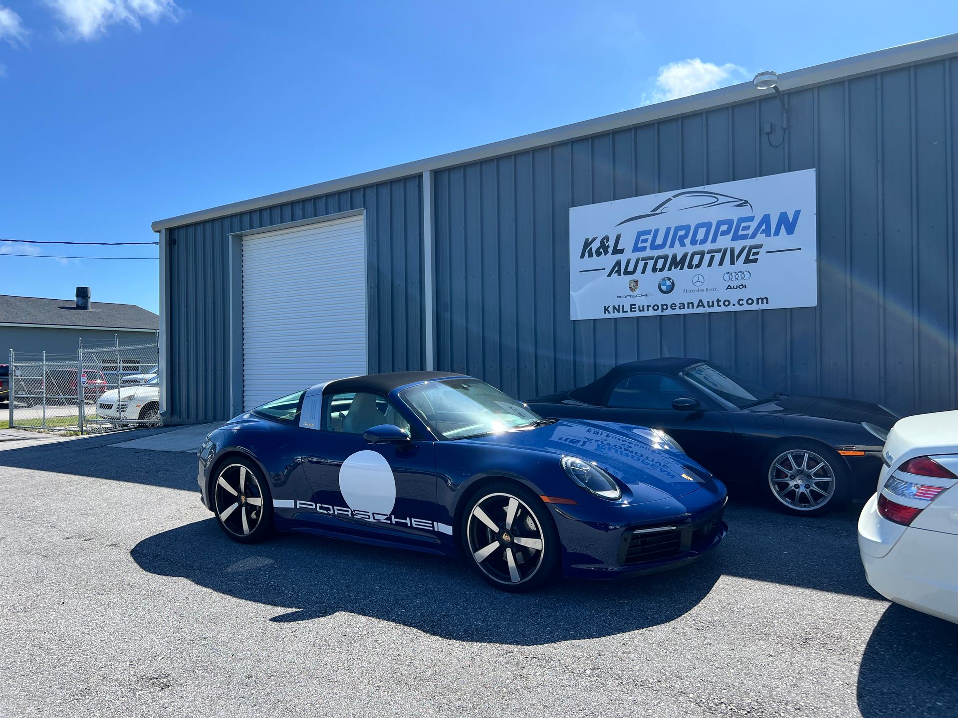 A blue porsche targa is parked in front of a building.