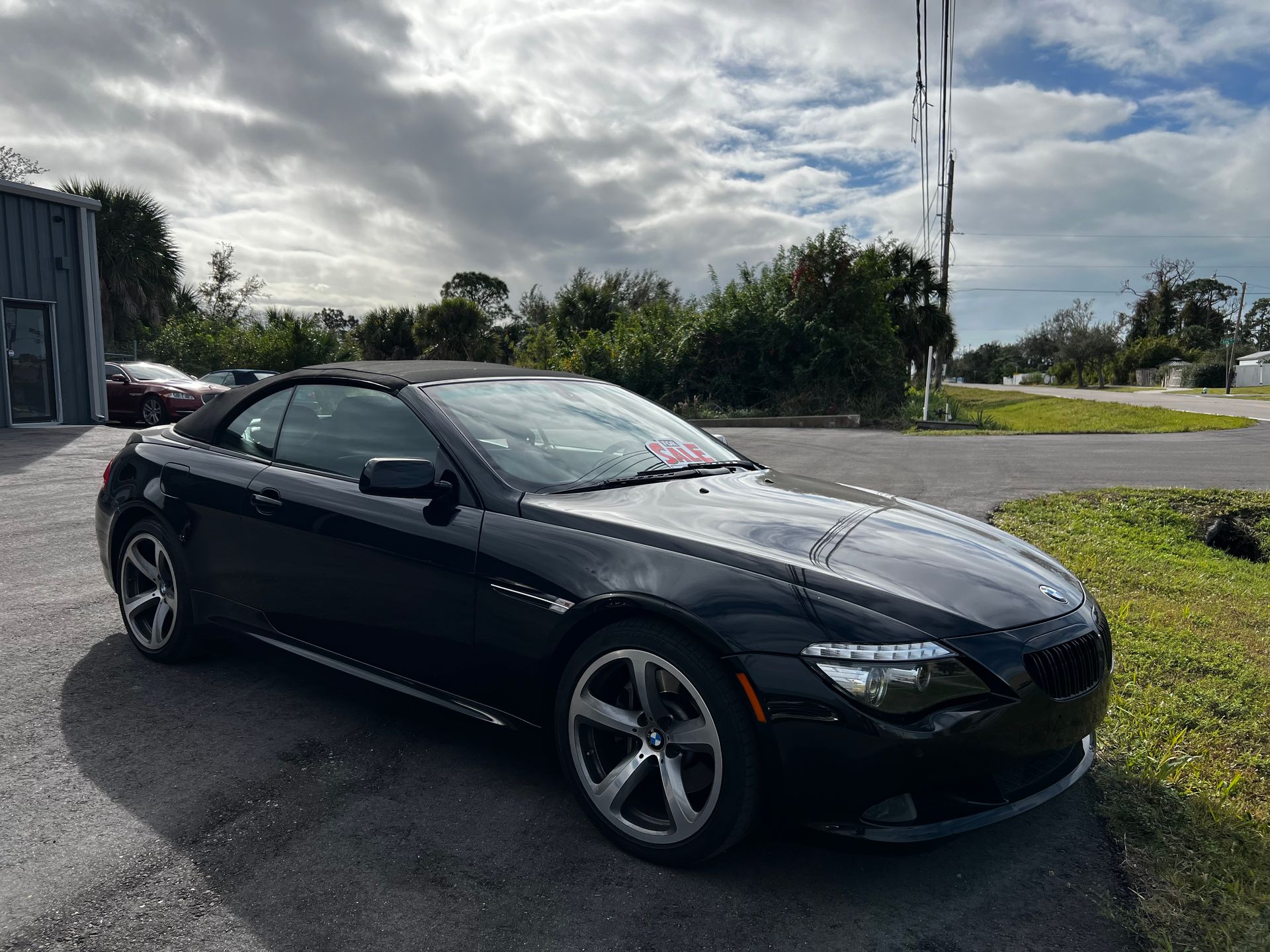 A black bmw 6 series convertible is parked on the side of the road.