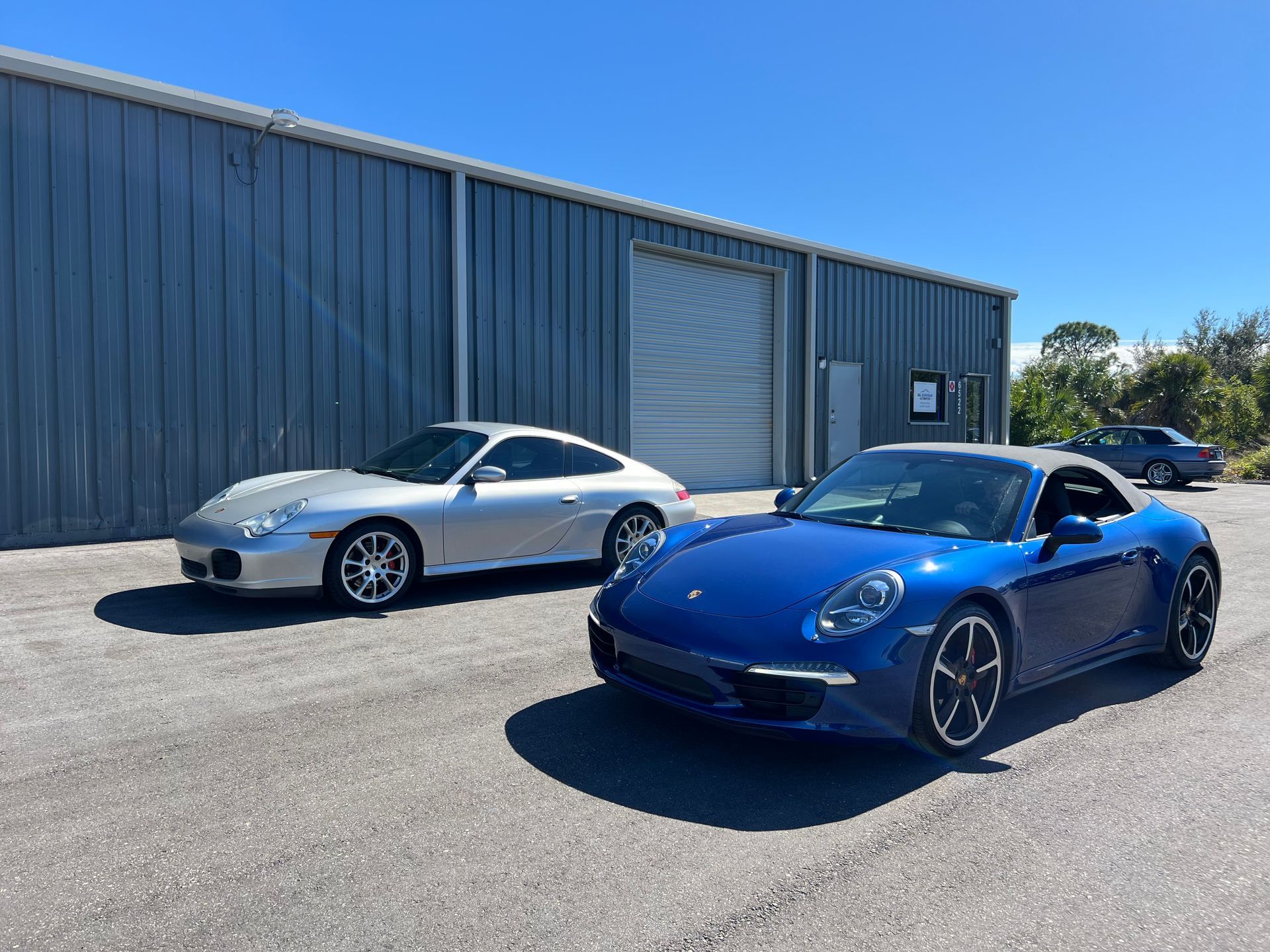 Two porsche cars are parked next to each other in front of a building.