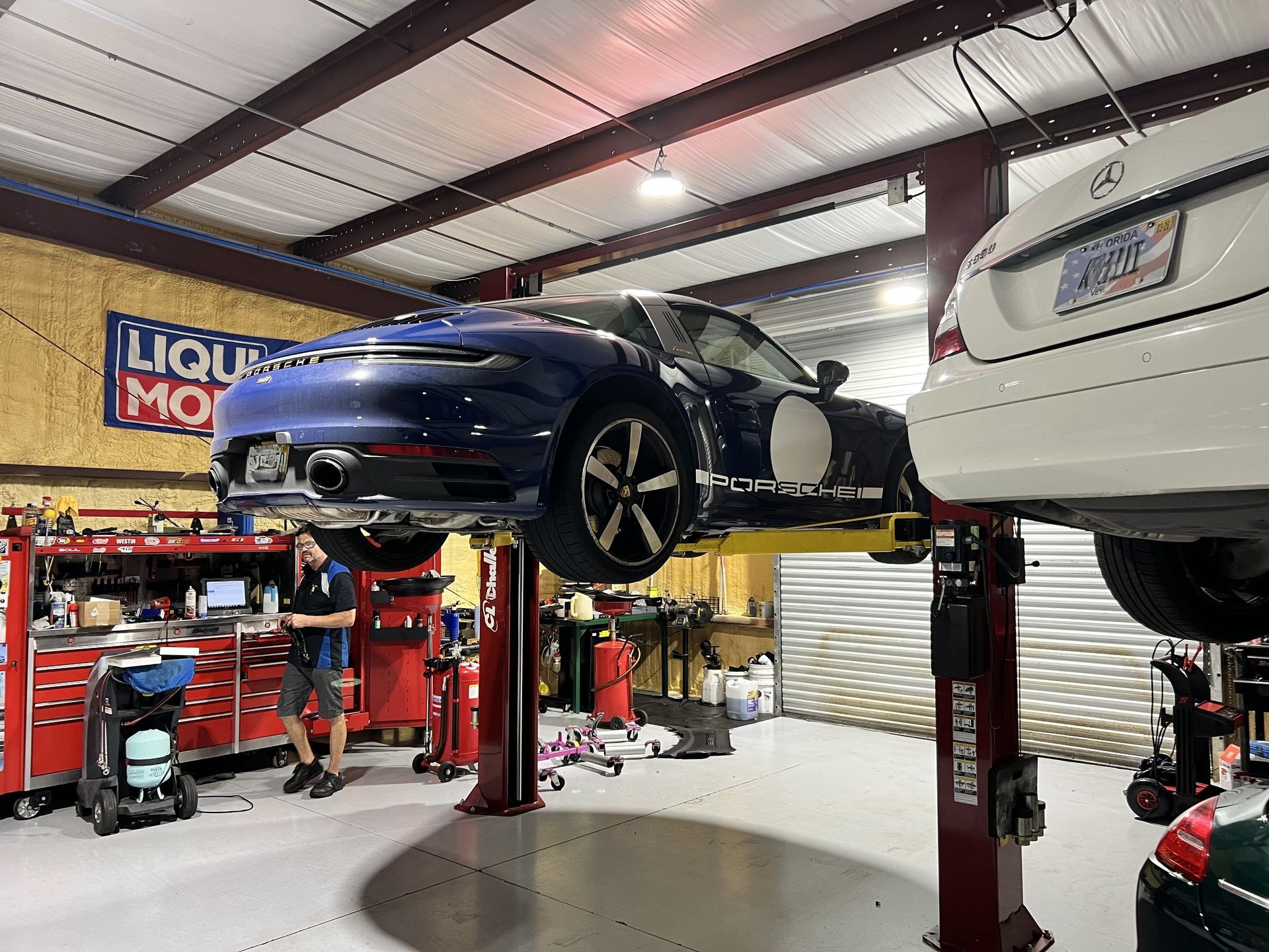 A blue car is sitting on a lift in a garage.