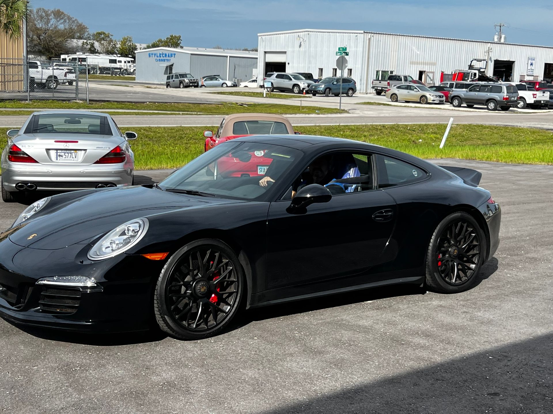 A black porsche 911 is parked in a parking lot