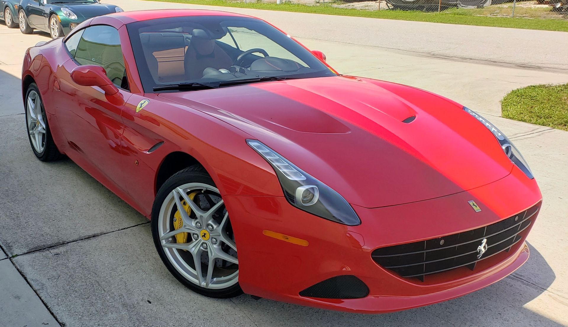 A red ferrari is parked on the side of the road.