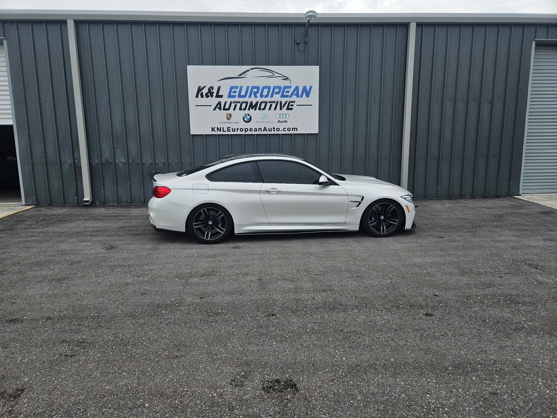 A white bmw m4 is parked in front of a building.